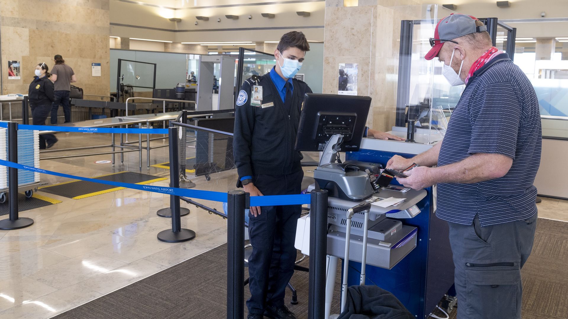 A TSA agent helping a passenger through a security checkpoint at John Wayne Airport in Santa Ana, California, in January 2021.