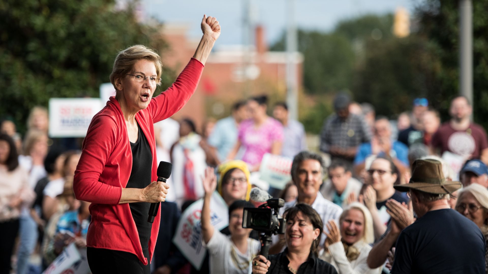 Elizabeth Warren, with her arm raised in a fist, speaks before a rally.