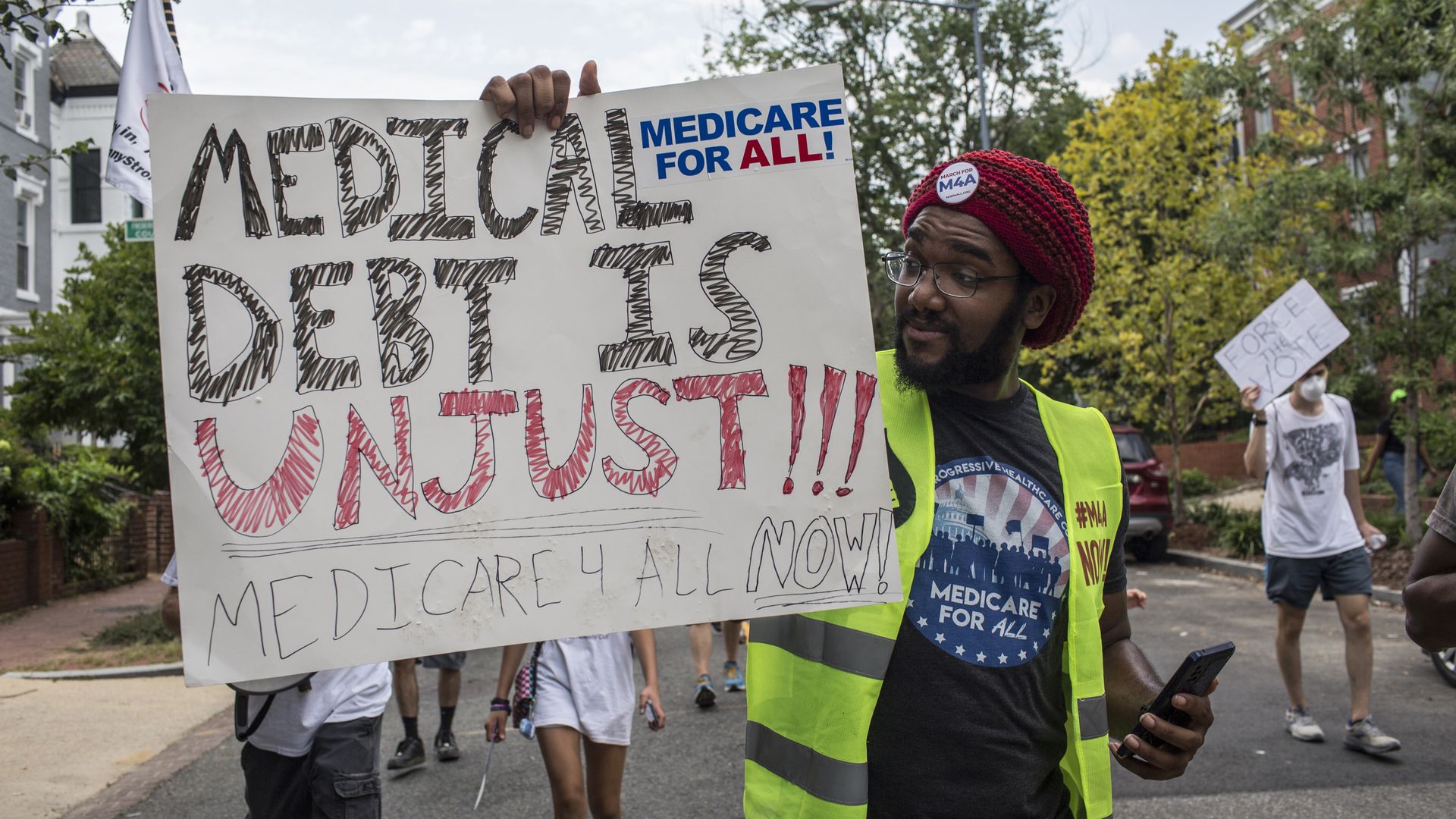 A man holding a sign with "Medical debt is unjust written" on it