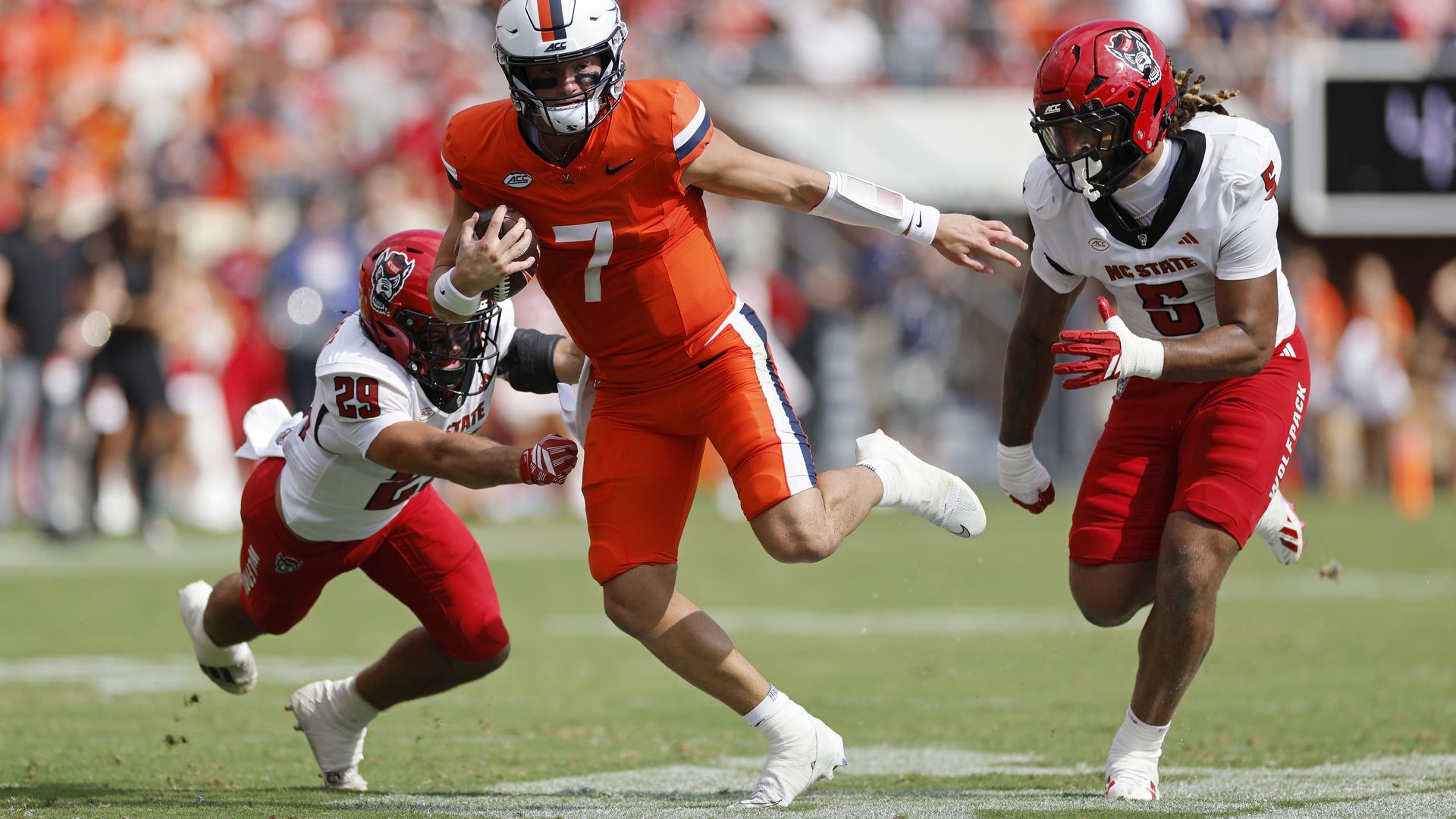 A quarterback runs past two defenders.