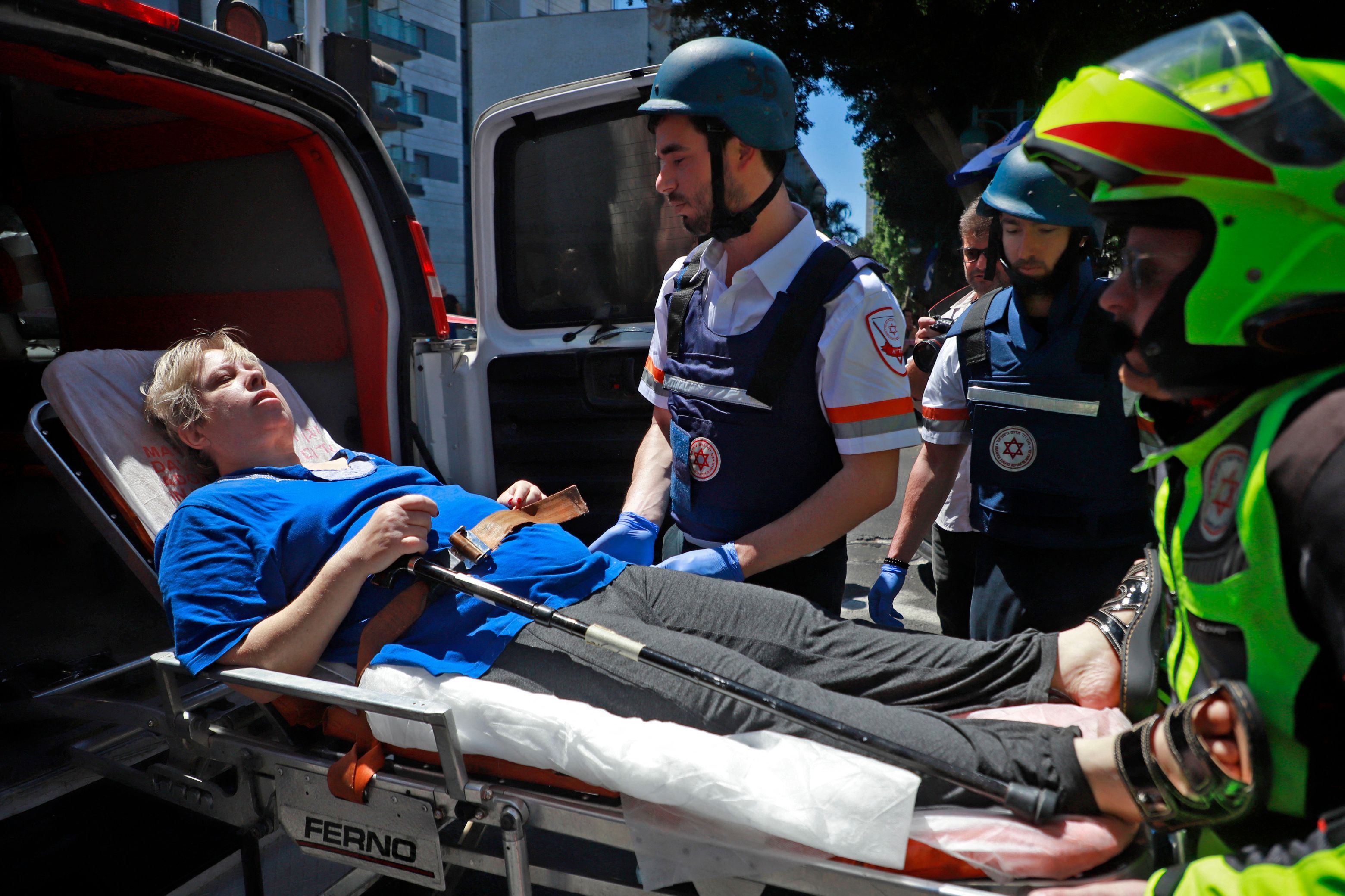 Members of Israeli security and emergency services transport an injured woman from a site hit by a rocket in Ramat Gan near the coastal city of Tel Aviv, on May 15