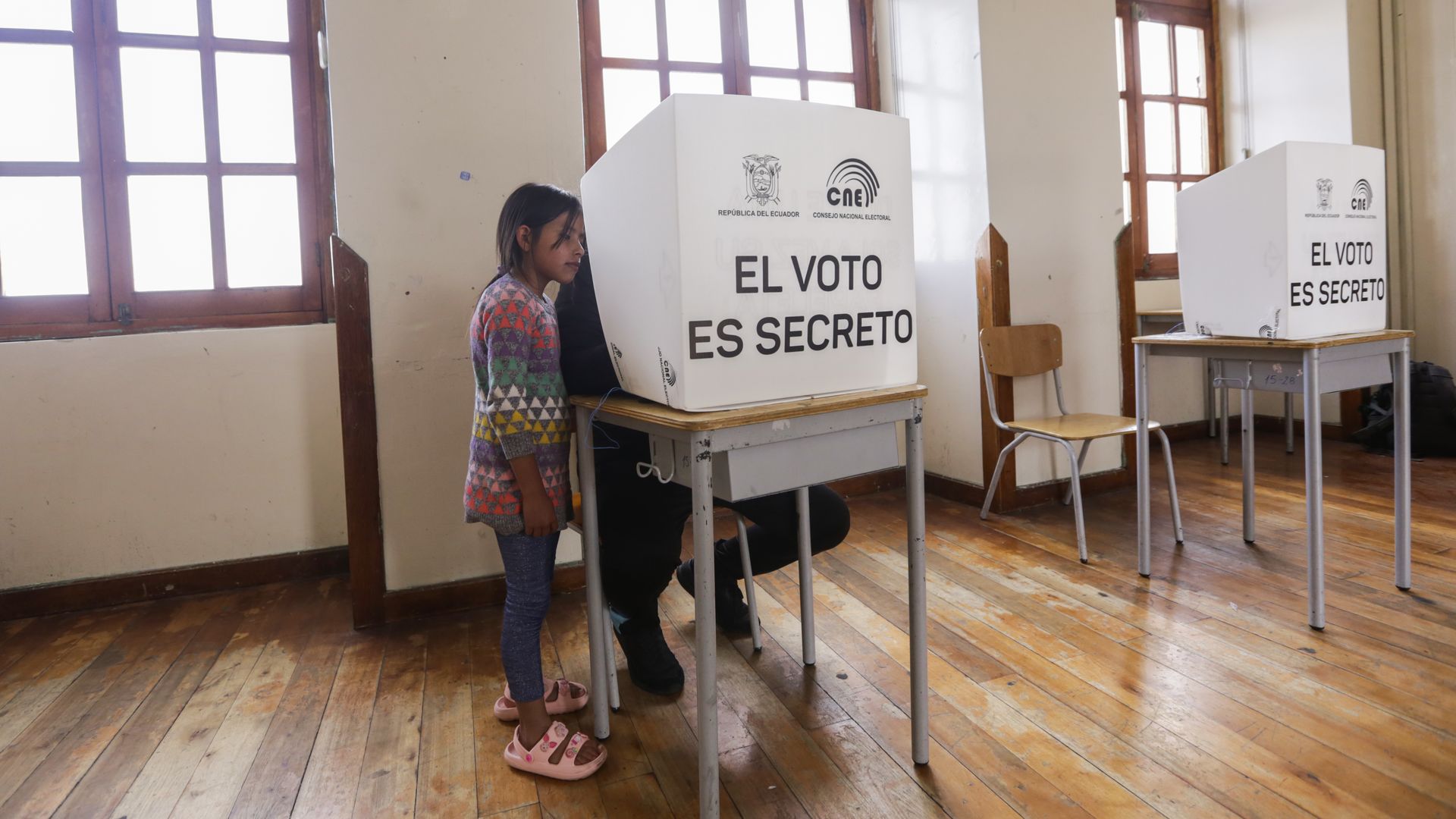 A girl looking at a man voting in a booth in Quito on Aug. 20.