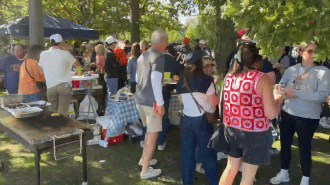 A GIF of a tailgate before a football game along a park. 