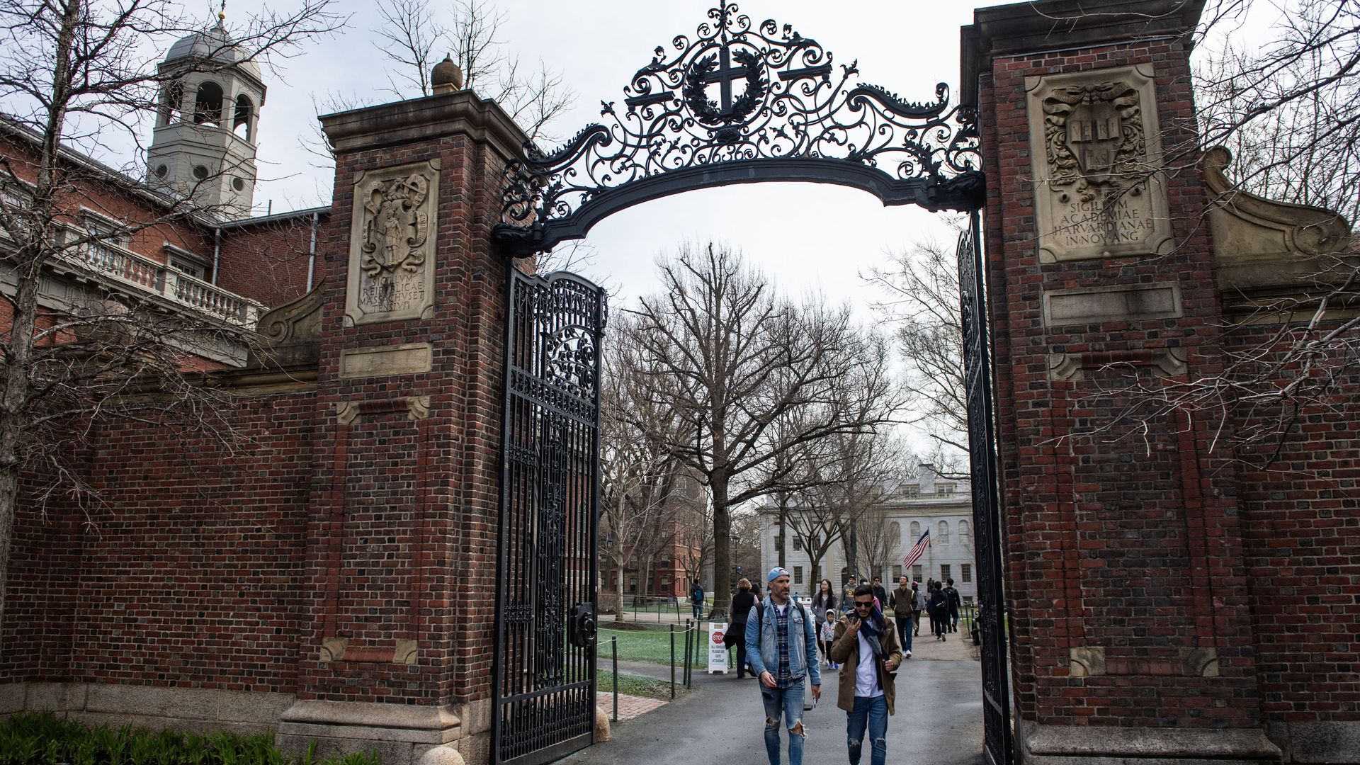 People walk through a gate as they exit Harvard Yard on the campus of Harvard University campus in Cambridge, Massachussetts, on April 15, 2025. Elite US university Harvard was hit with a $2.2 billion federal funding freeze on April 14 after rejecting a list of sweeping demands that the White House 