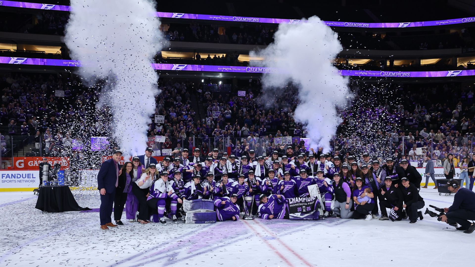 A women's ice hockey team in purple uniforms celebrates on ice with confetti and smoke effects; holding a trophy and banner that reads "Champions Minnesota Frost 2025".