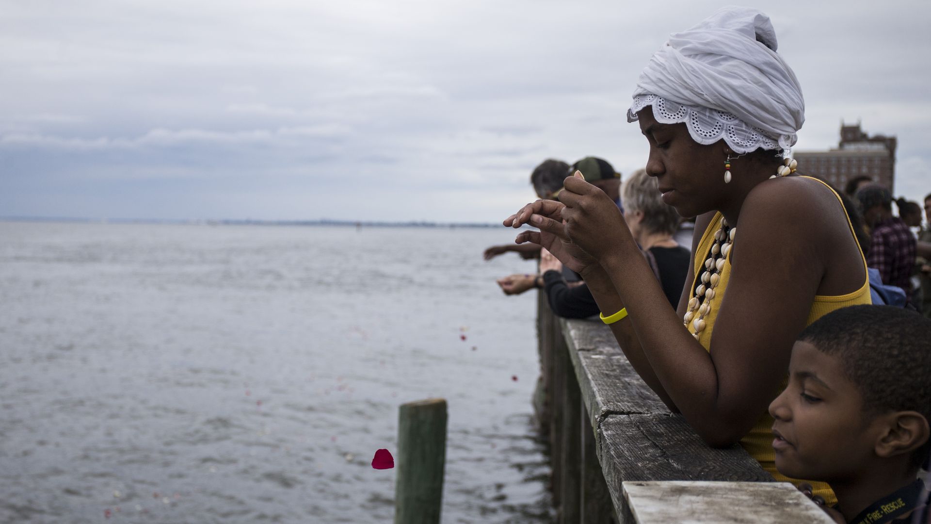 Guests take part in a flower petal throwing ceremony to honor Africans who passed away at sea during the Atlantic slave trade during the 2019 African Landing Commemorative Ceremony on August 24