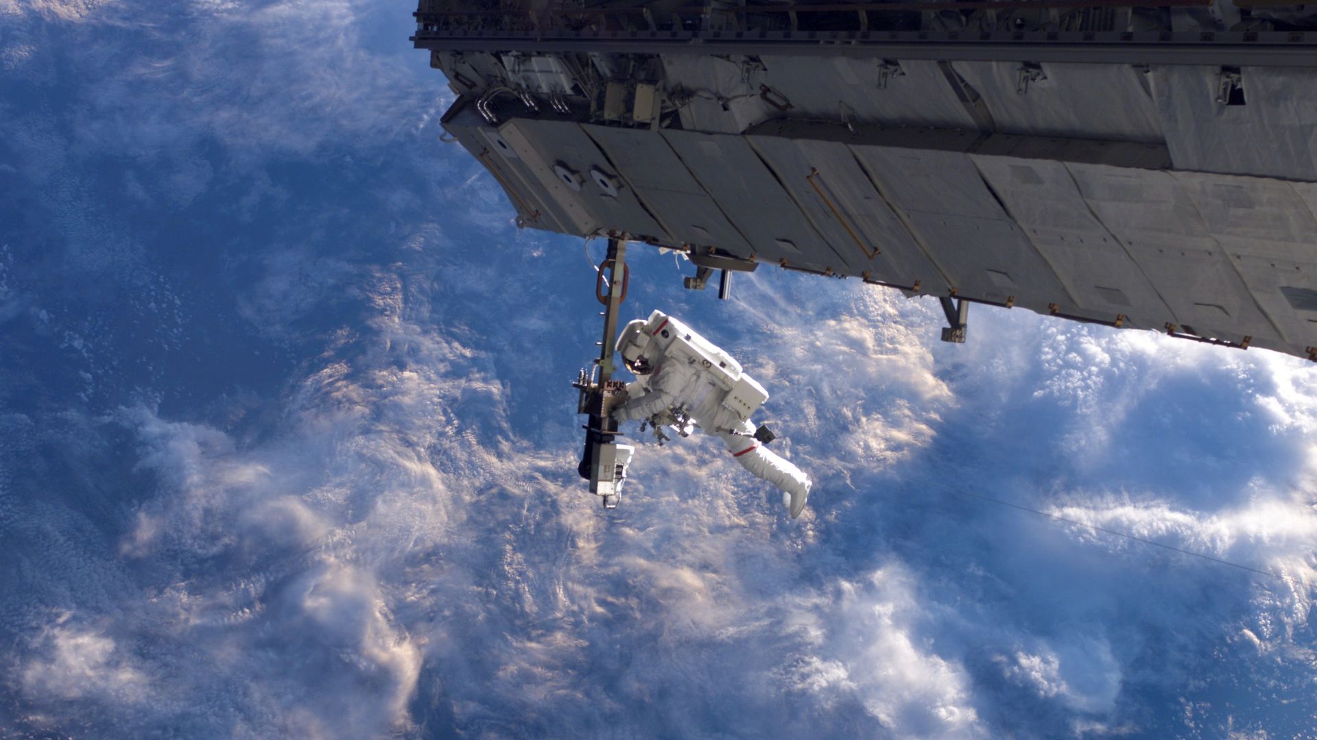 An astronaut on a spacewalk seen above the Earth