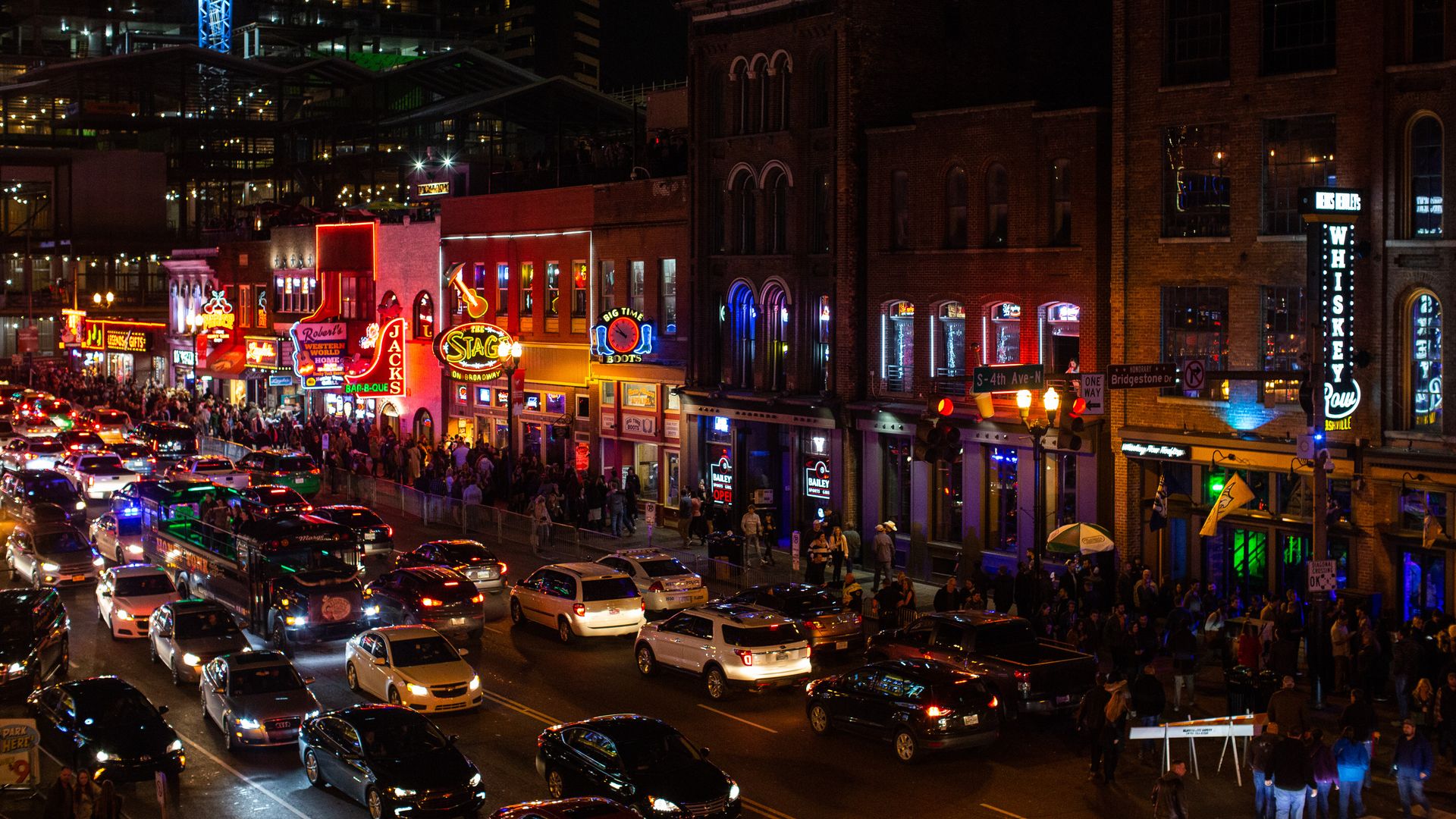 Lower Broadway at night, with neon honky tonk signs glowing on the traffic-stuffed streets