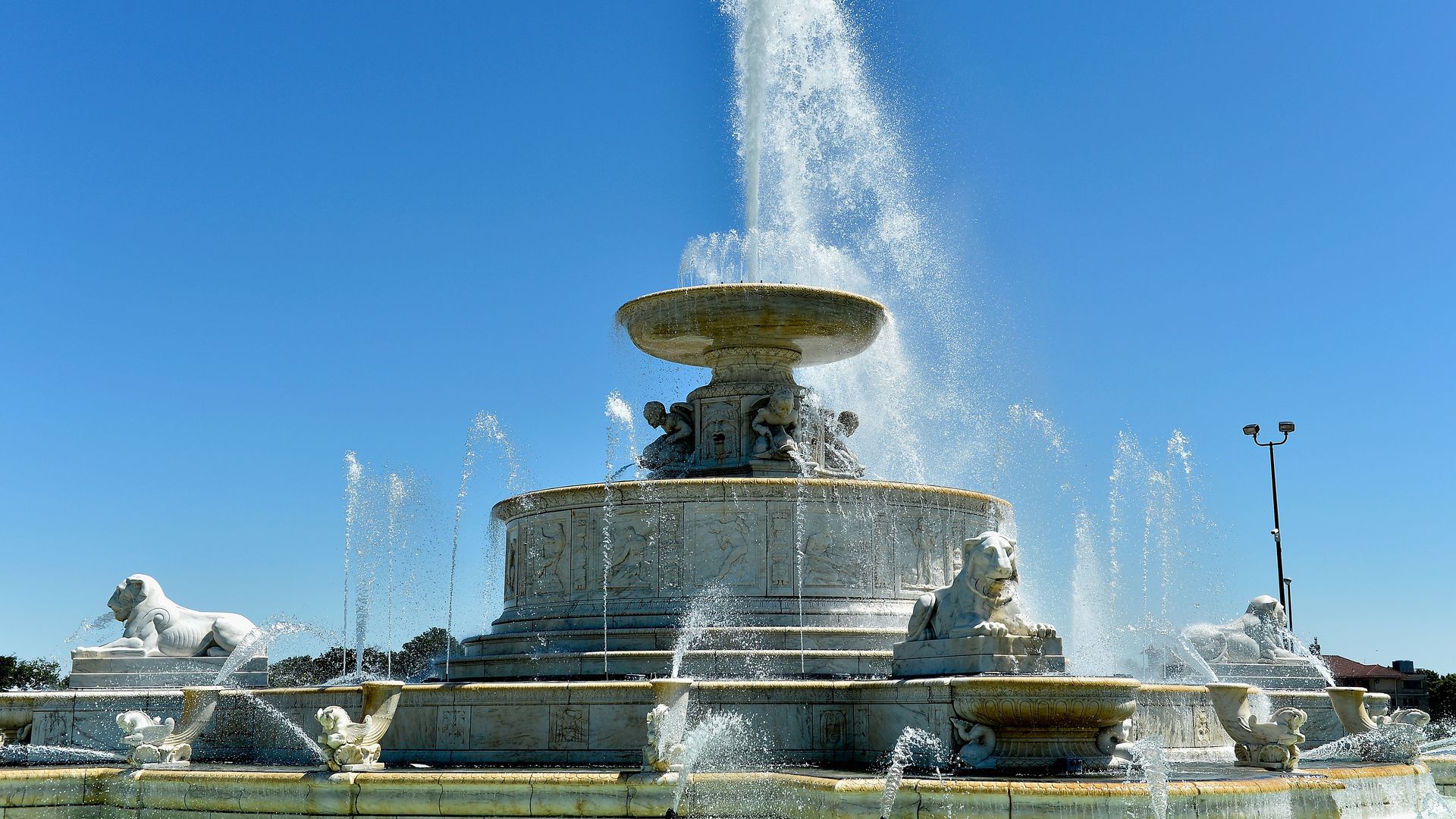 The fountain spurts up, statuesque, against a blue sky.