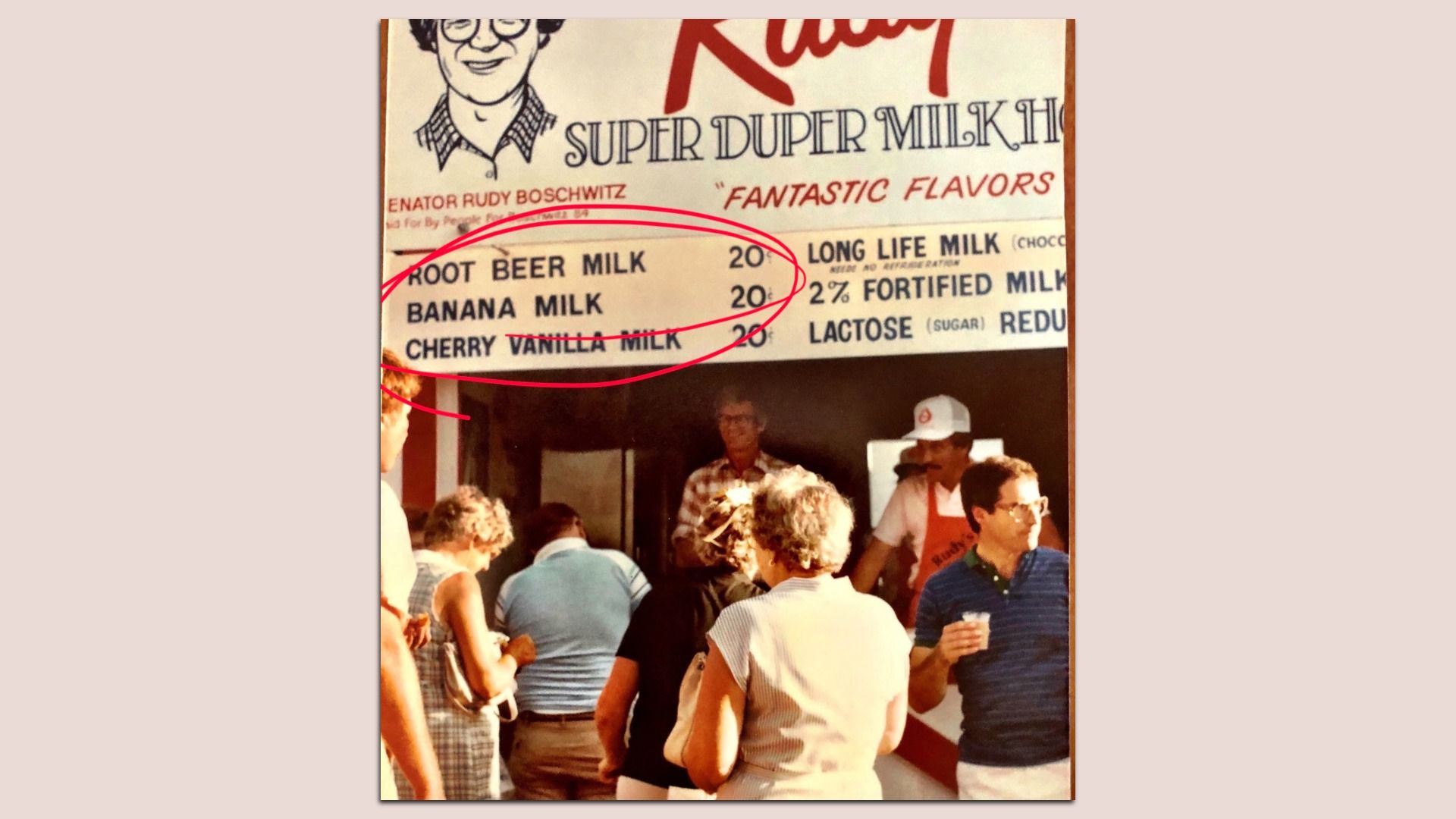 Vintage photo of a crowd at a counter beneath a sign listing milk flavors—Root Beer Milk, Banana Milk, and Cherry Vanilla Milk—circled in red.