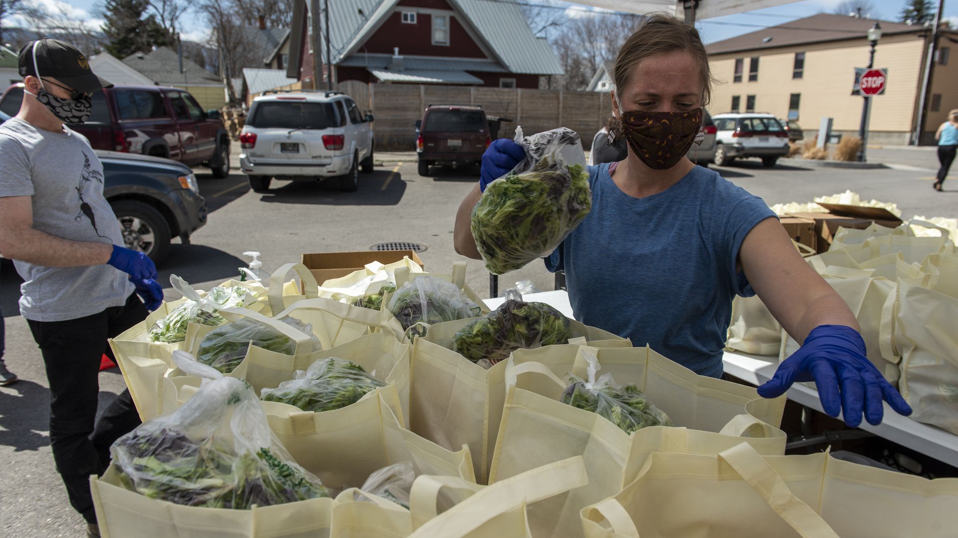 In this image, a masked woman handles grocery bags