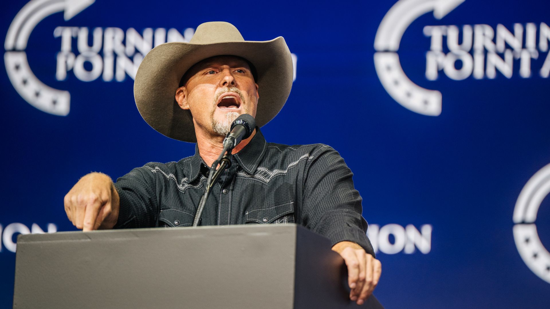 A man in a cowboy hate talking at a podium.