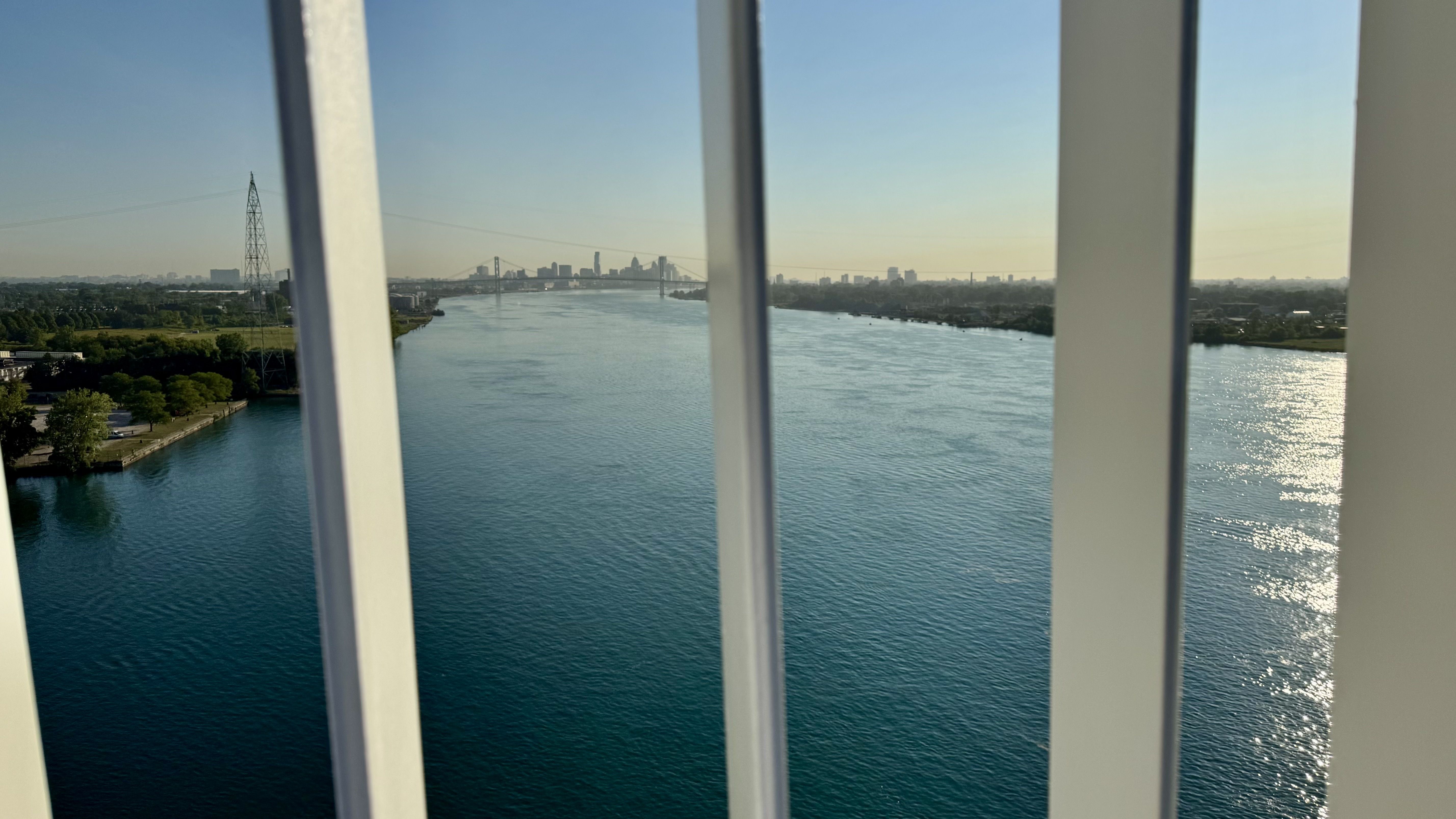 The view of the river and downtown from the bridge. Mostly clear but with thin poles breaking up the view.