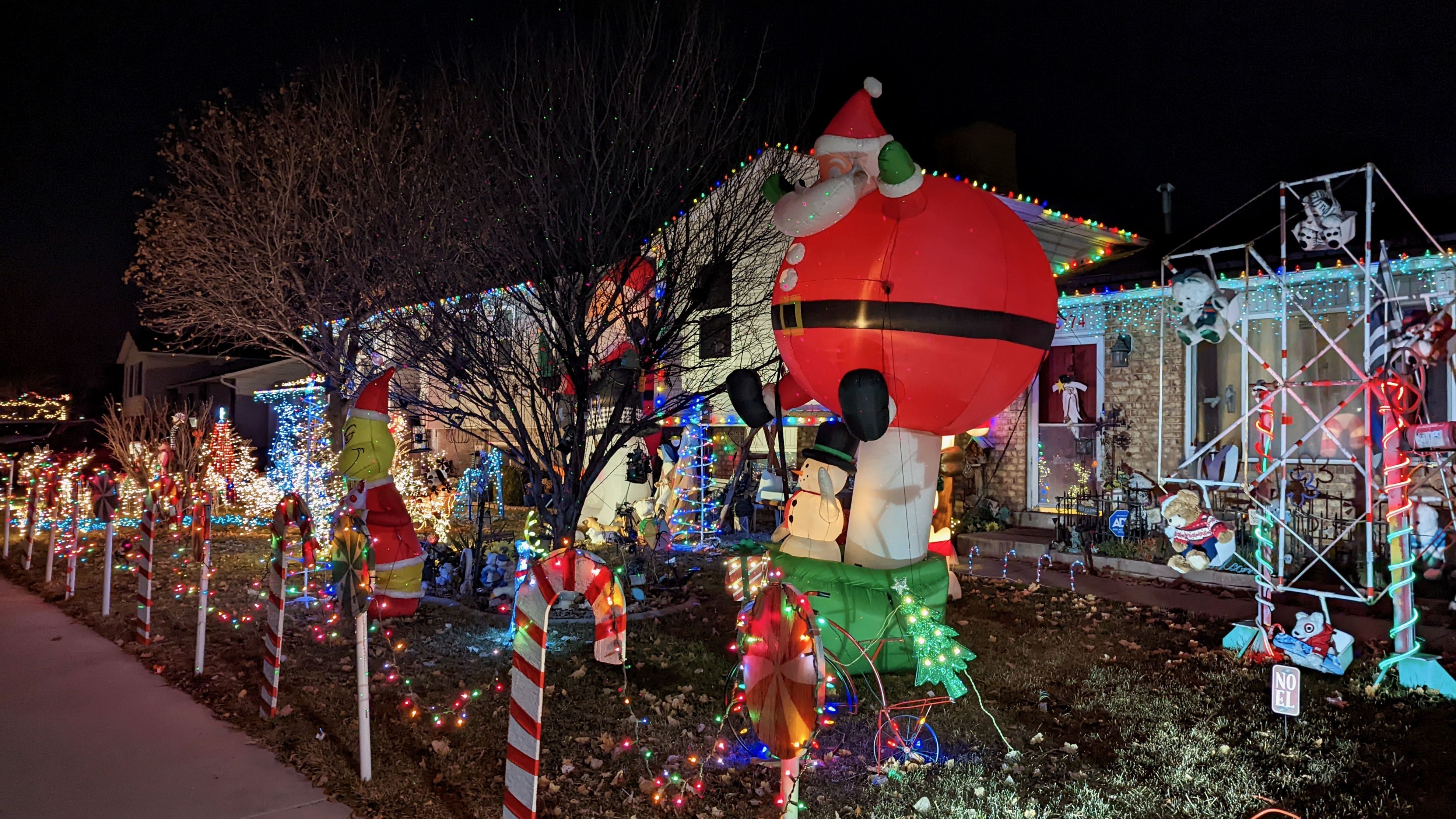 A Christmas carnival display across two residential yards, with a ferris wheel and giant santa.