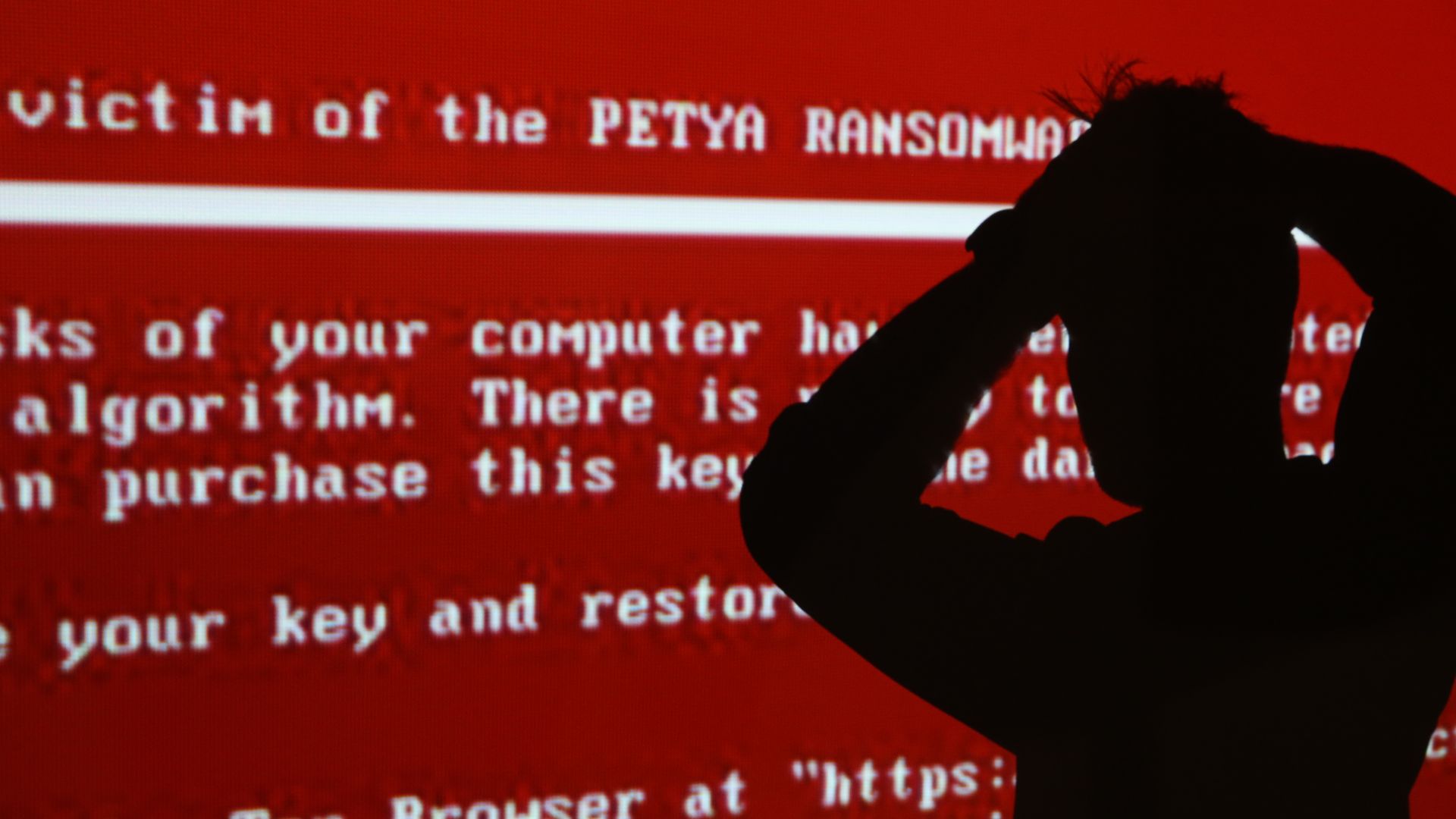 The silhouette of a young man against a red background with a projected message related to the Petya ransomware