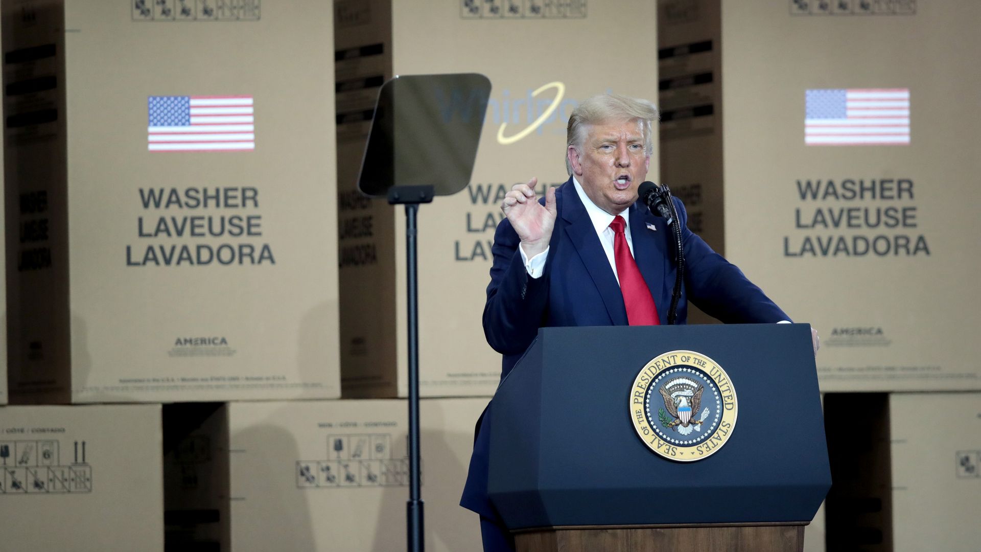 President Trump speaks at a podium with appliance boxes in the background.