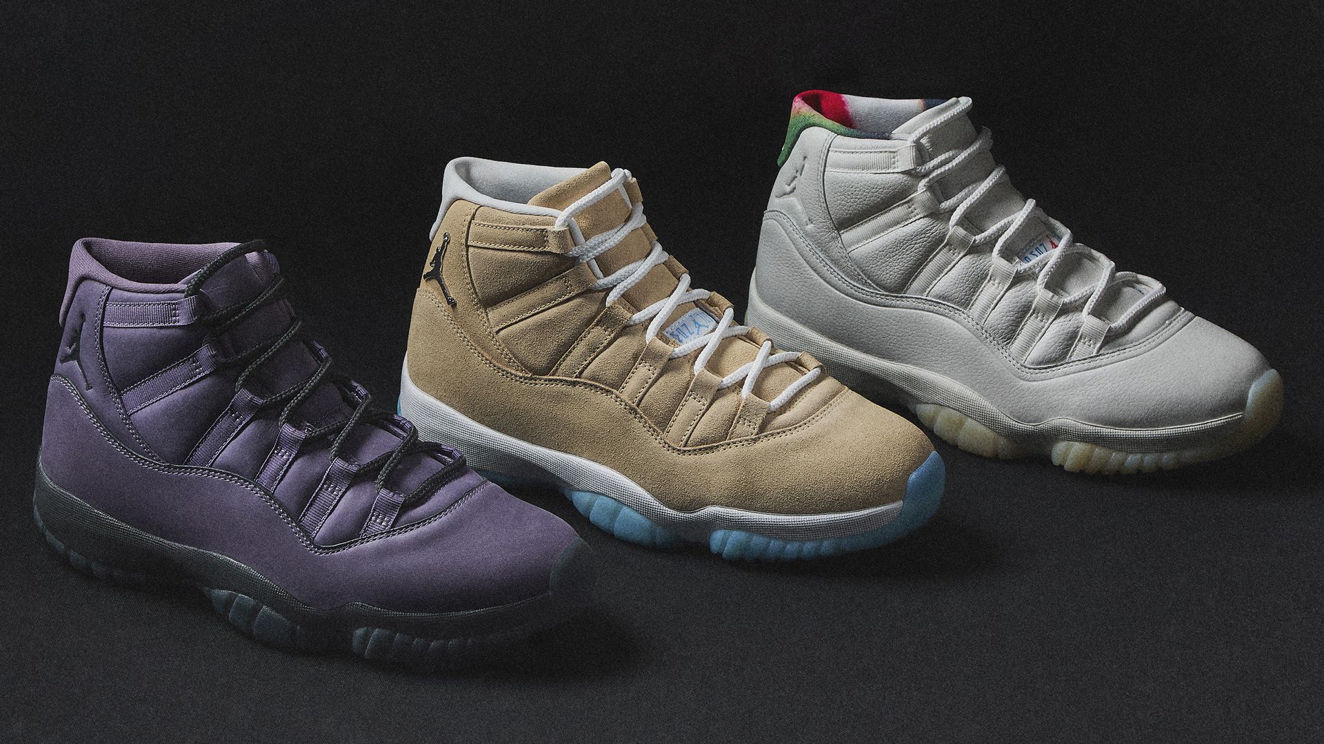 Three Air Jordan 11 sneakers in purple, tan with white laces and blue sole, and off-white with green and red accents, arranged on a black background.