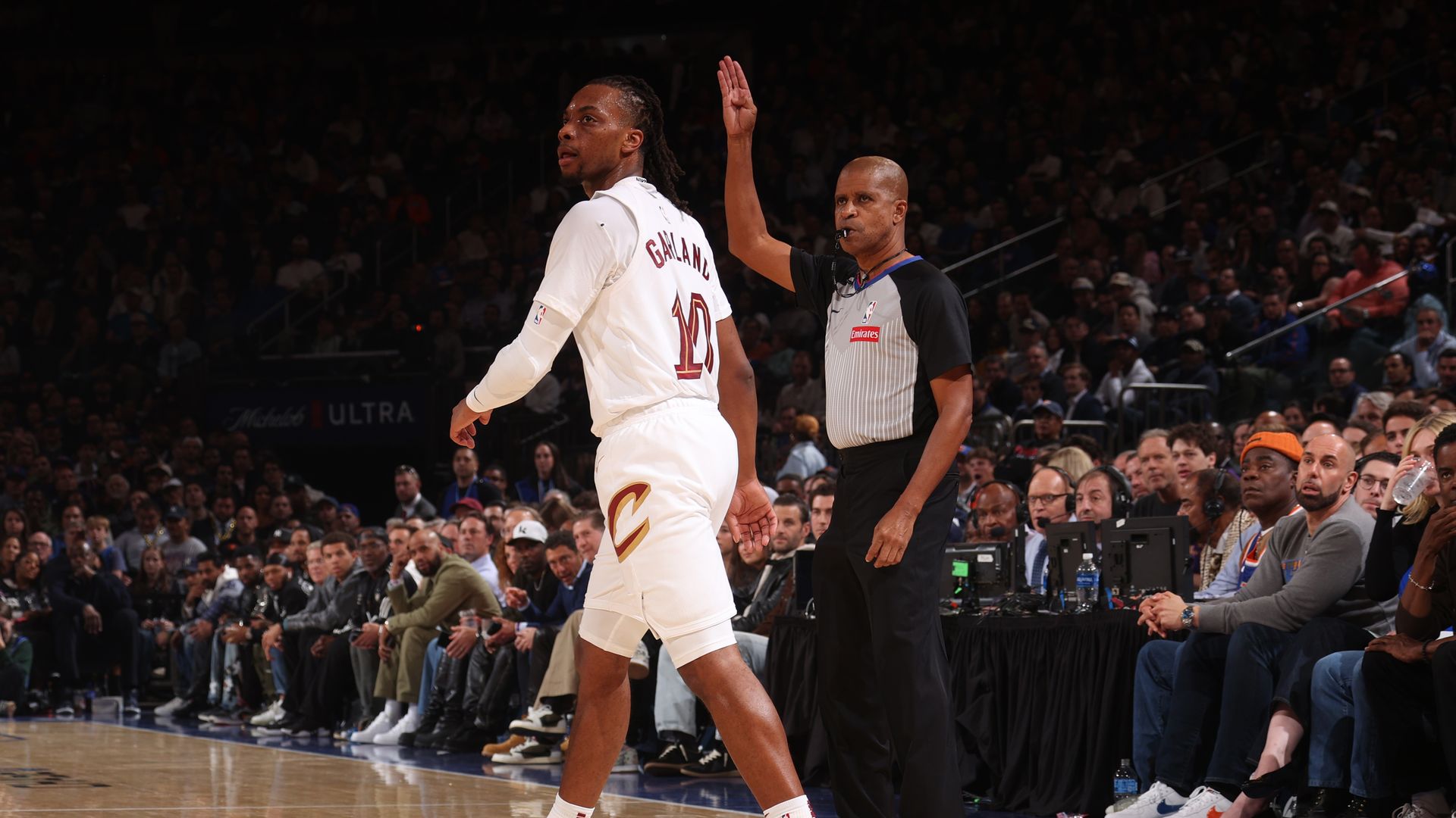 Cavs' Darius Garland eyes a jump shot while a referee behind him holds up his arm