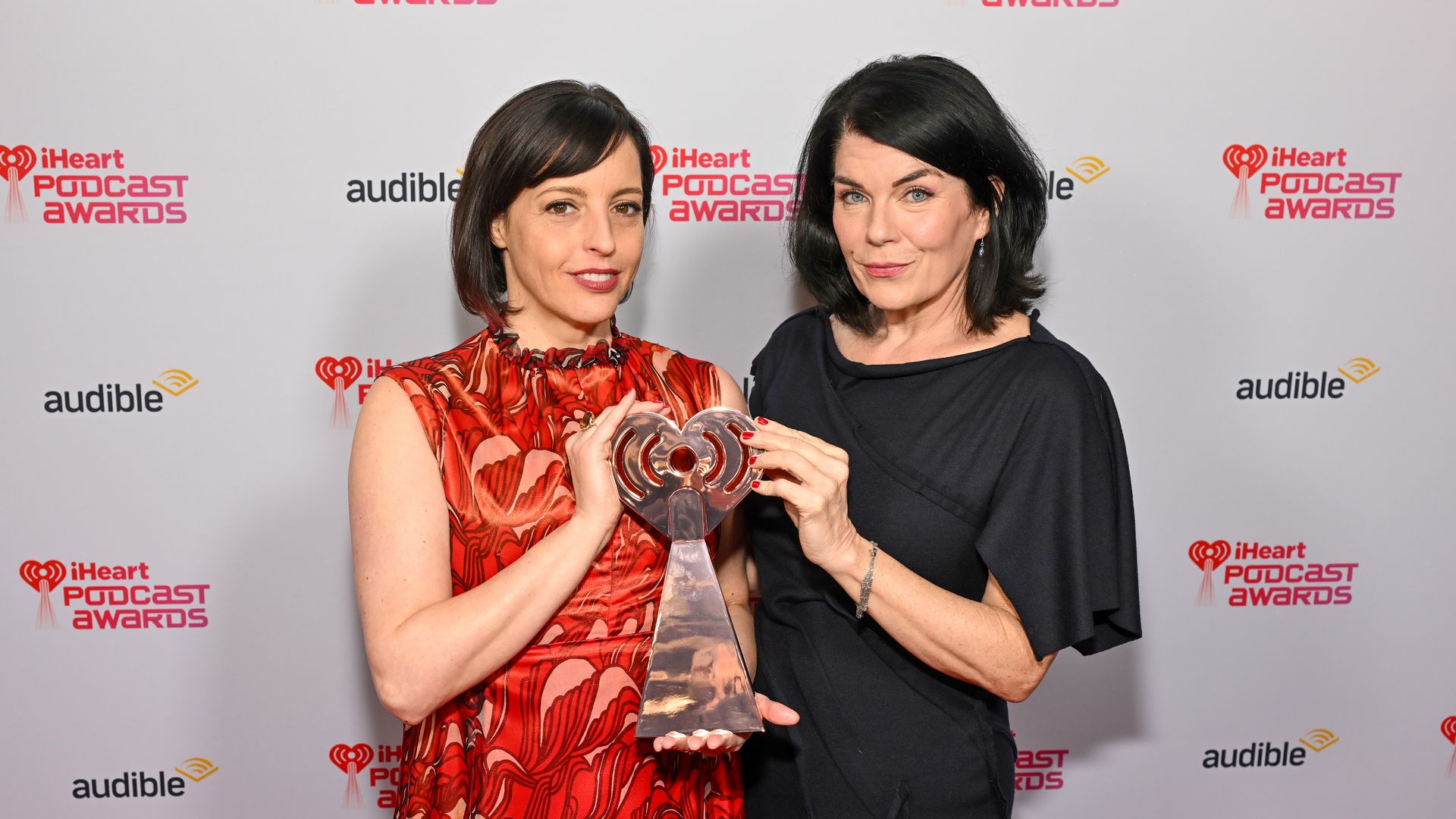 Two women hold an award.