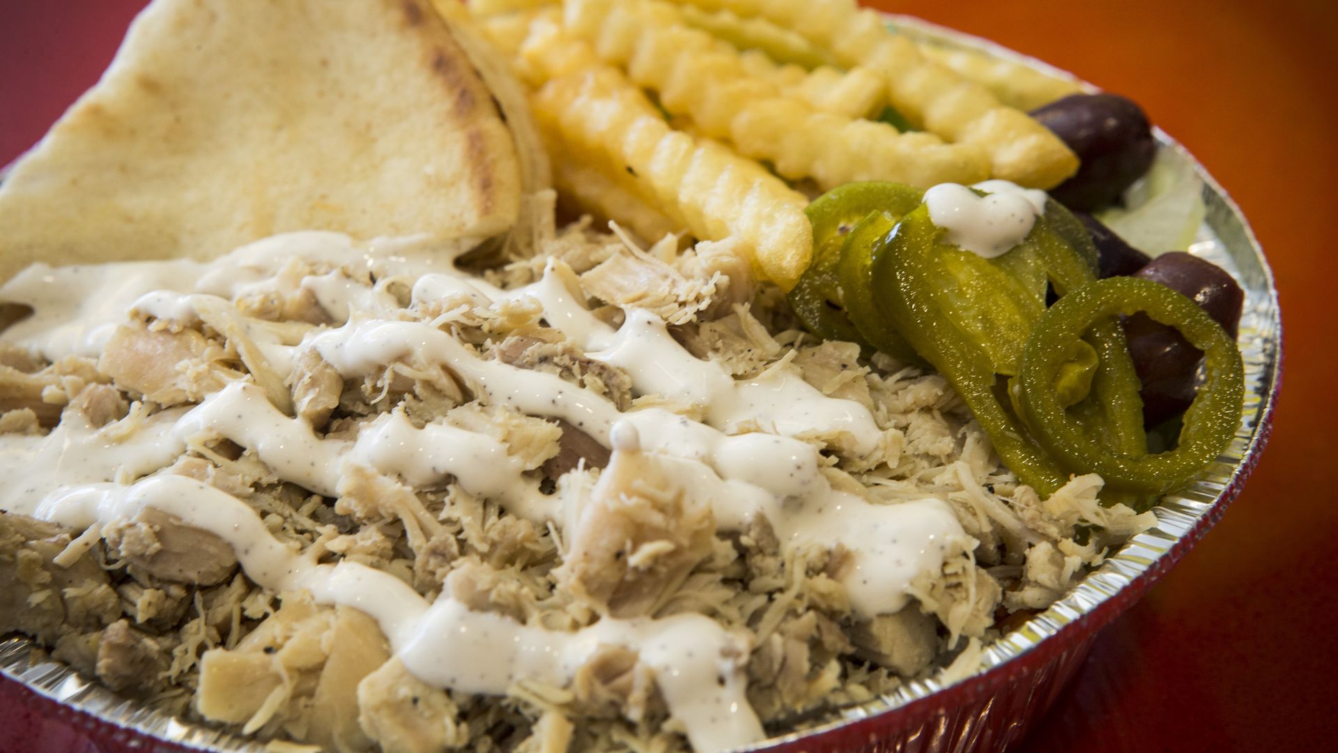 Chicken over rice plate, with extra jalapeño and olives and a side of fries, is shown at The Halal Guys at 3821 Farnham on Monday, Jan. 25, 2016, in Houston. The franchise of a famous New York City eatery where people line up for gyros and chicken covered in a secret sauce. ( Brett Coomer / Houston 
