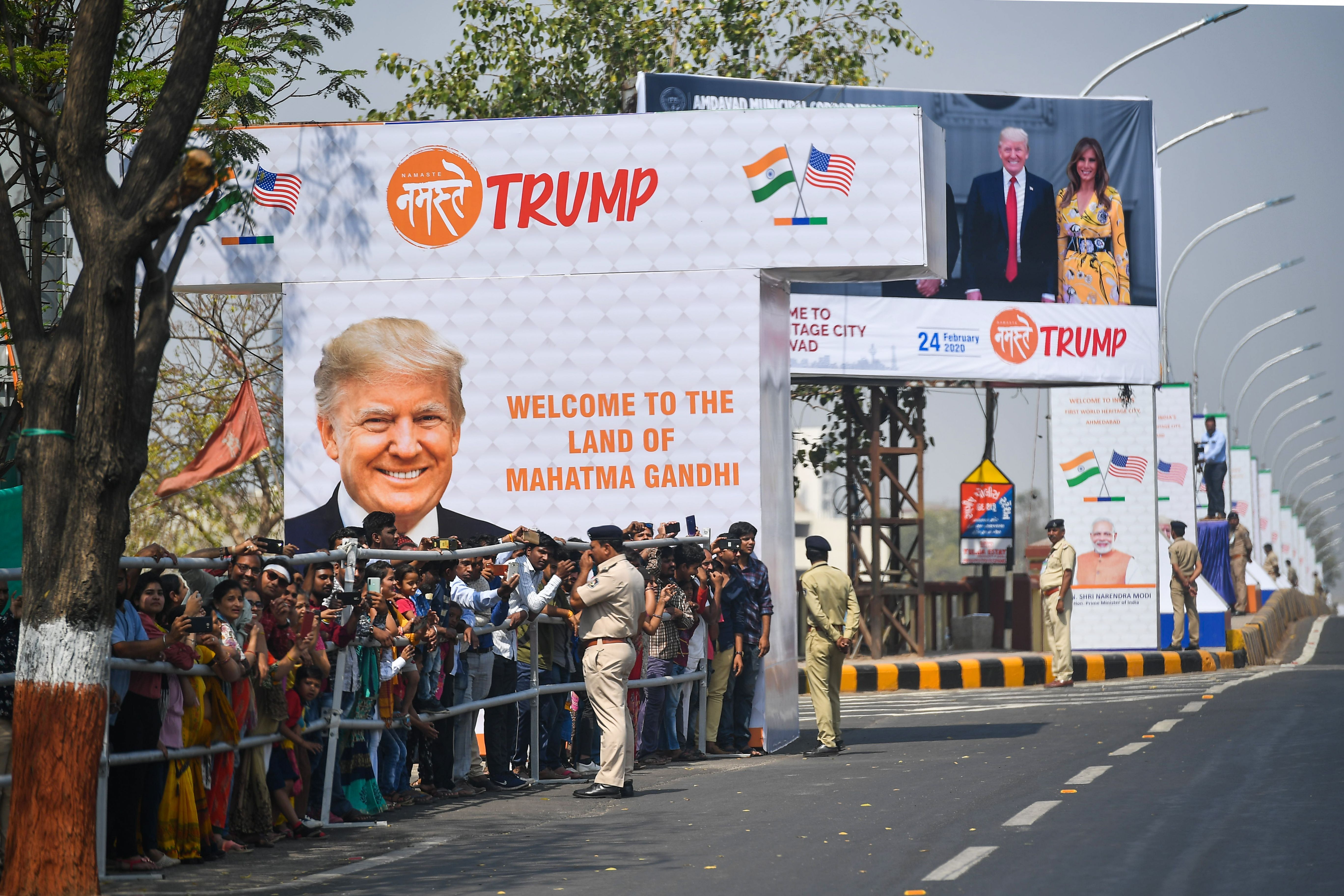 People gather beside a street as a motorcade transporting US President Donald Trump makes its way in Ahmedabad on February 24