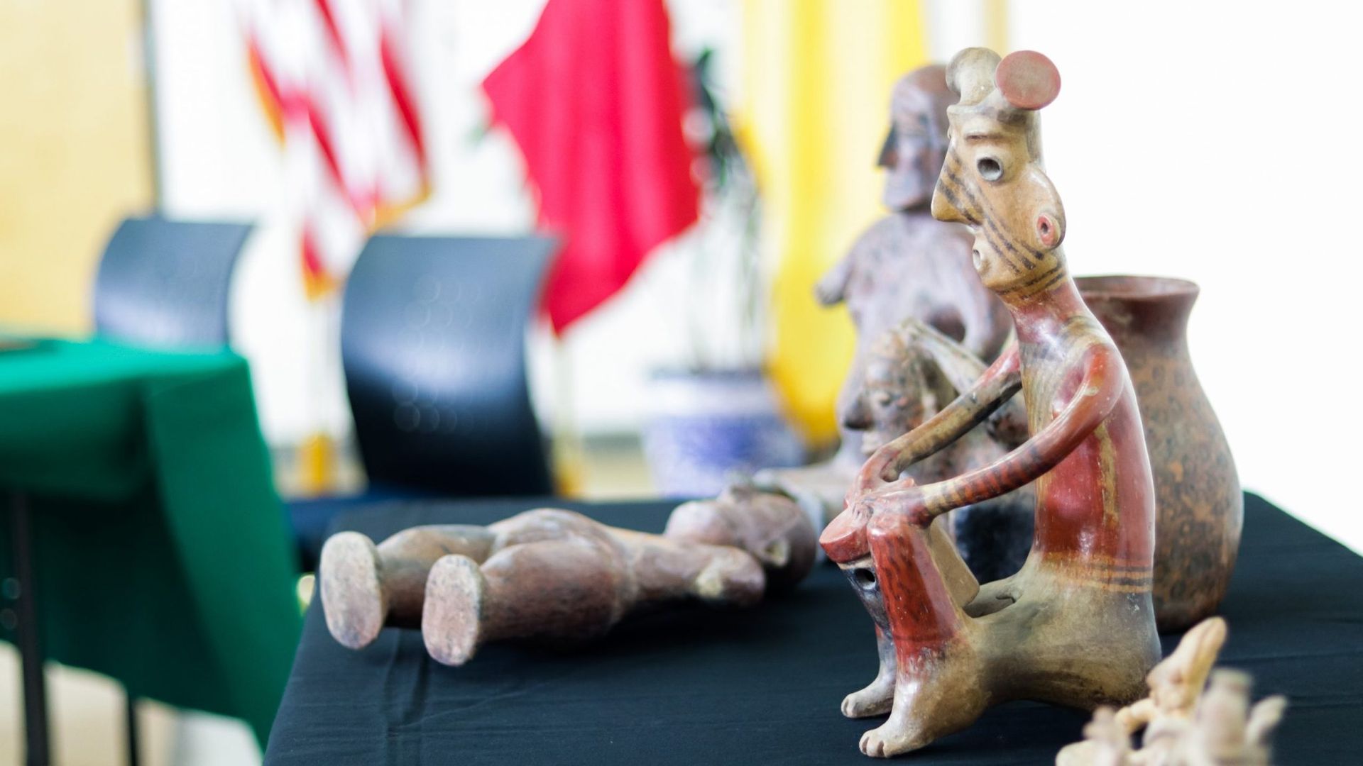an ancient Mexican sculpture of a person sitting with their knees up is shown