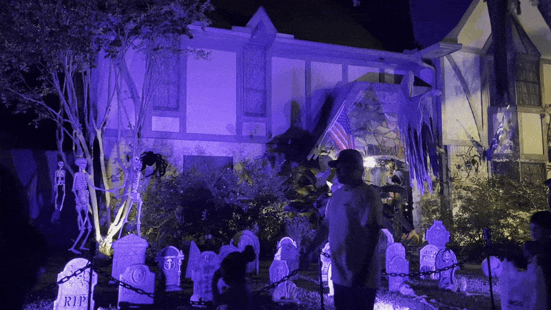Image shows trick or treaters walking in front of a house decorated for Halloween.