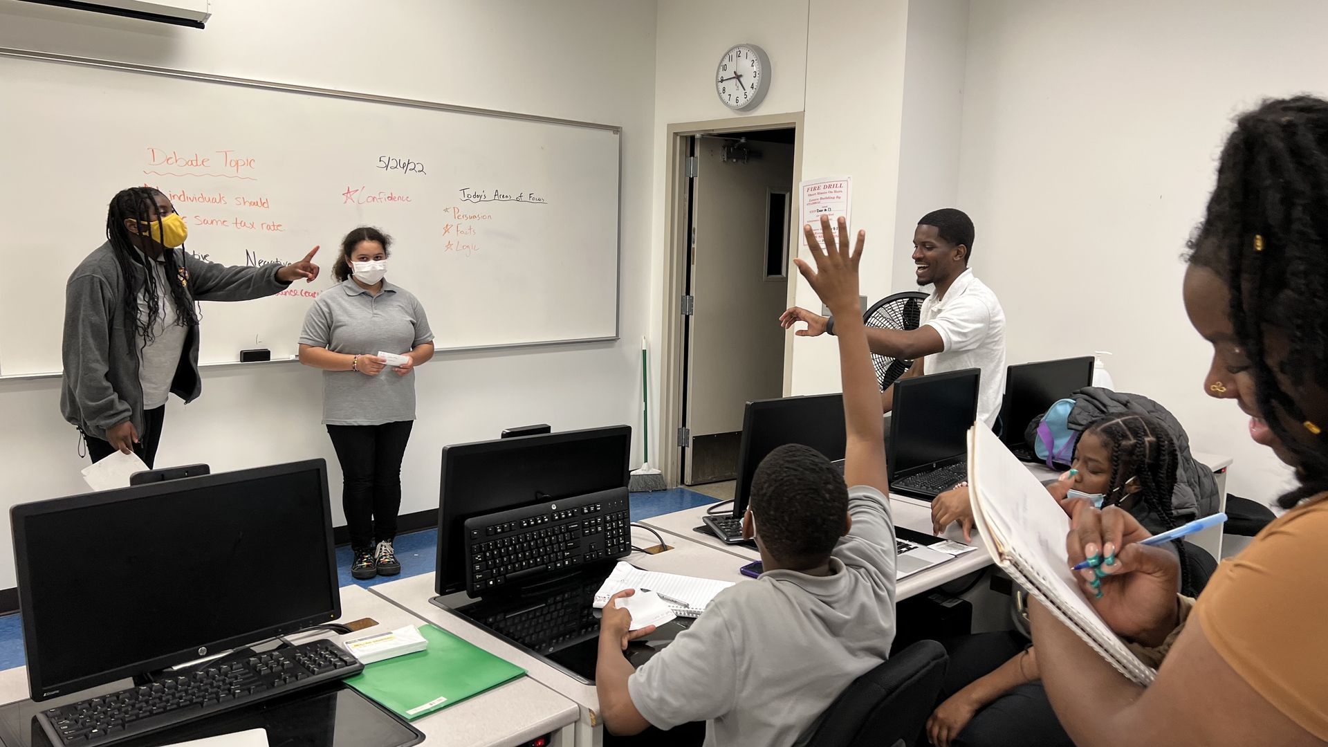 John R King students take turns debating topics in front of the whiteboard like "should Americans pay a flat tax rate?"