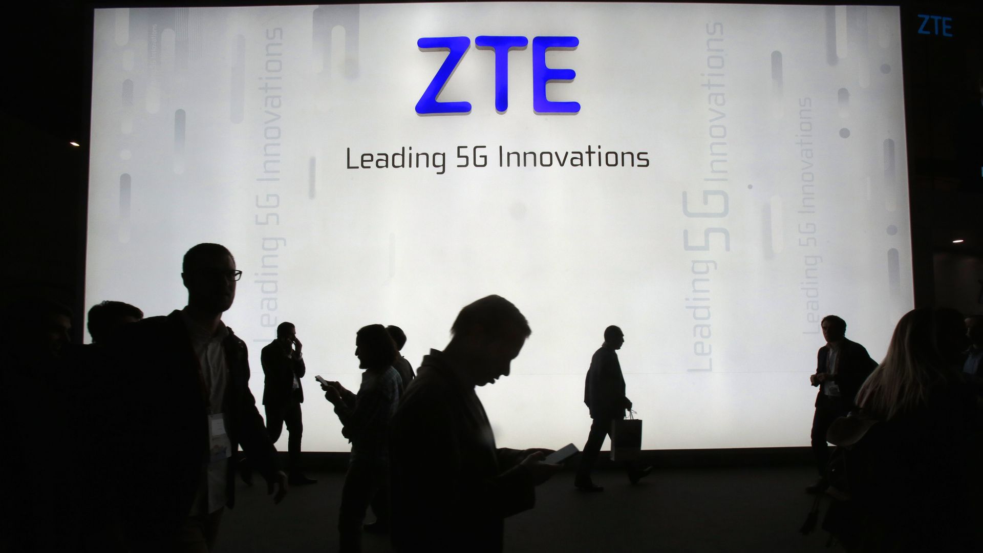 Figures silhouetted in front of the ZTE logo