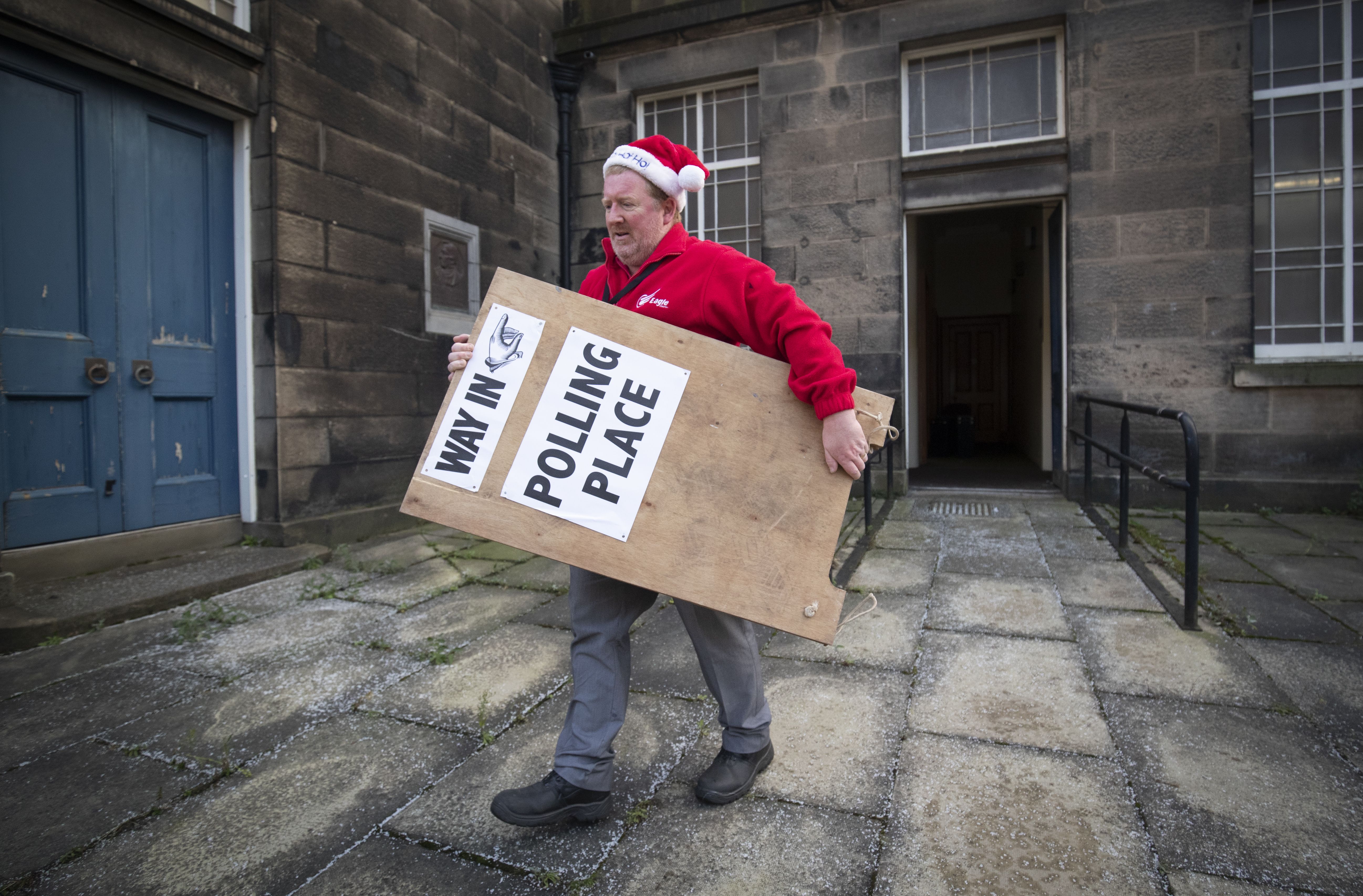 Brian Mansley carries a sign, one of hundreds that are being dispatched to polling stations around Scotland from the Old Royal High School in Edinburgh
