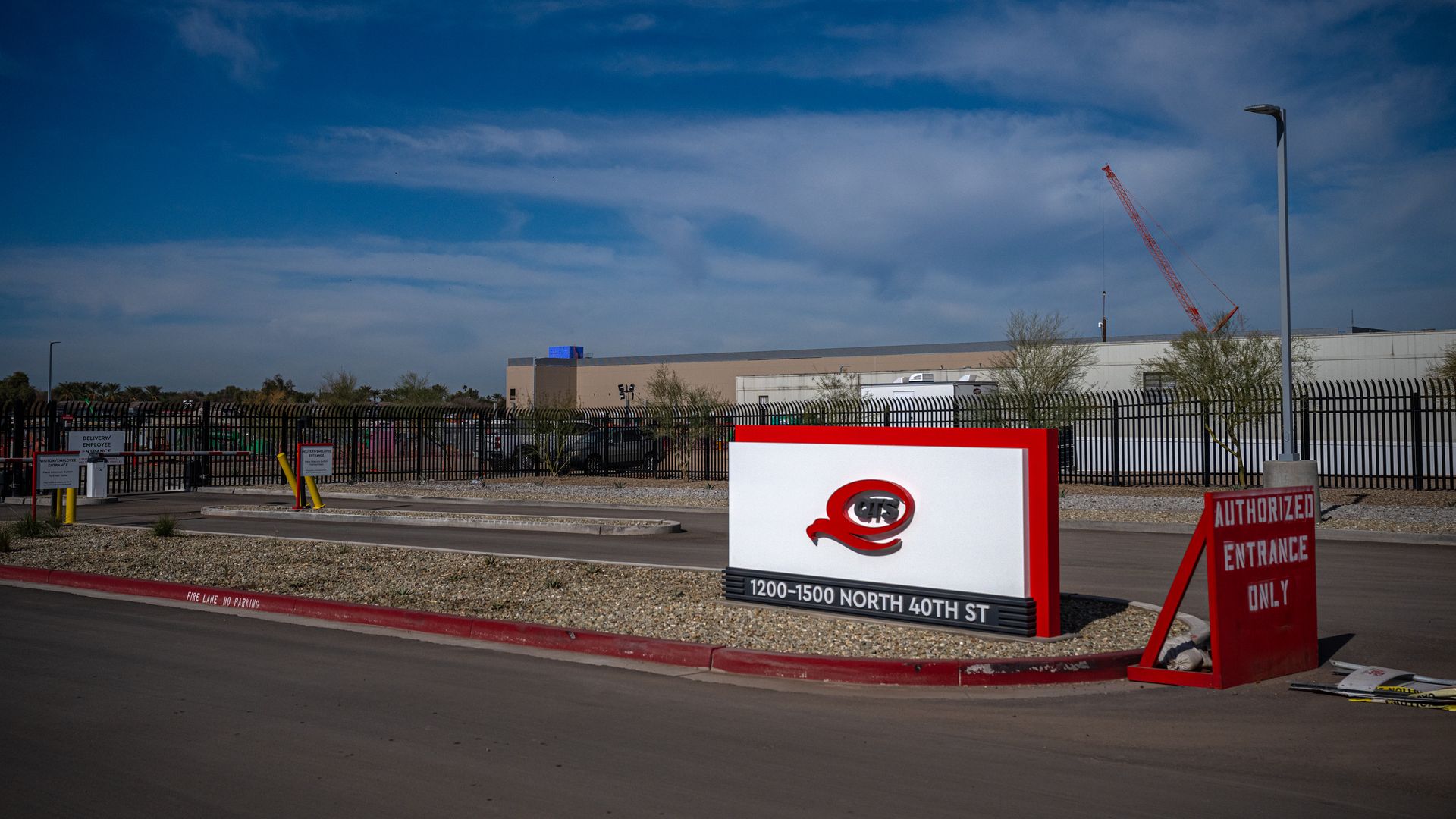 The front of a data center with a black metal fence around it. 