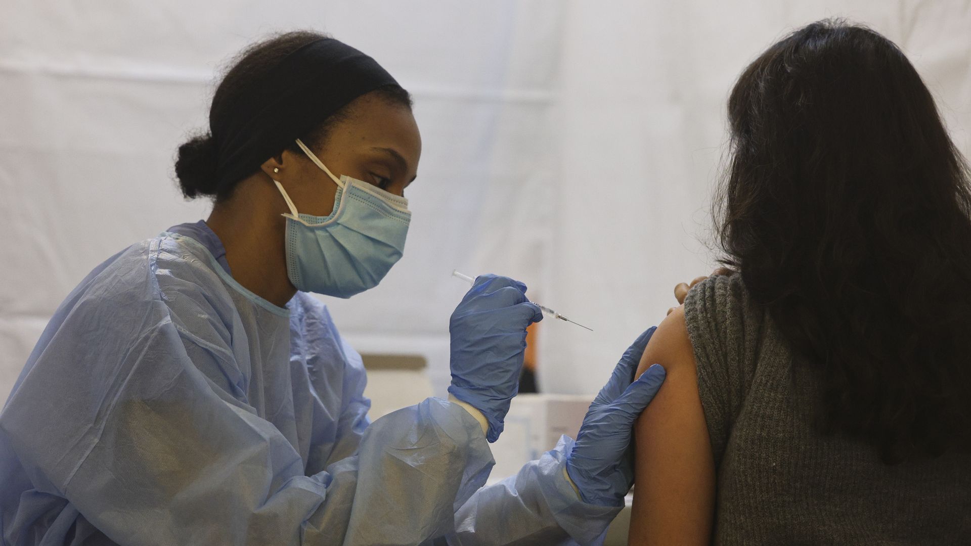 A health care worker administers a COVID-19 vaccine in the Bronx
