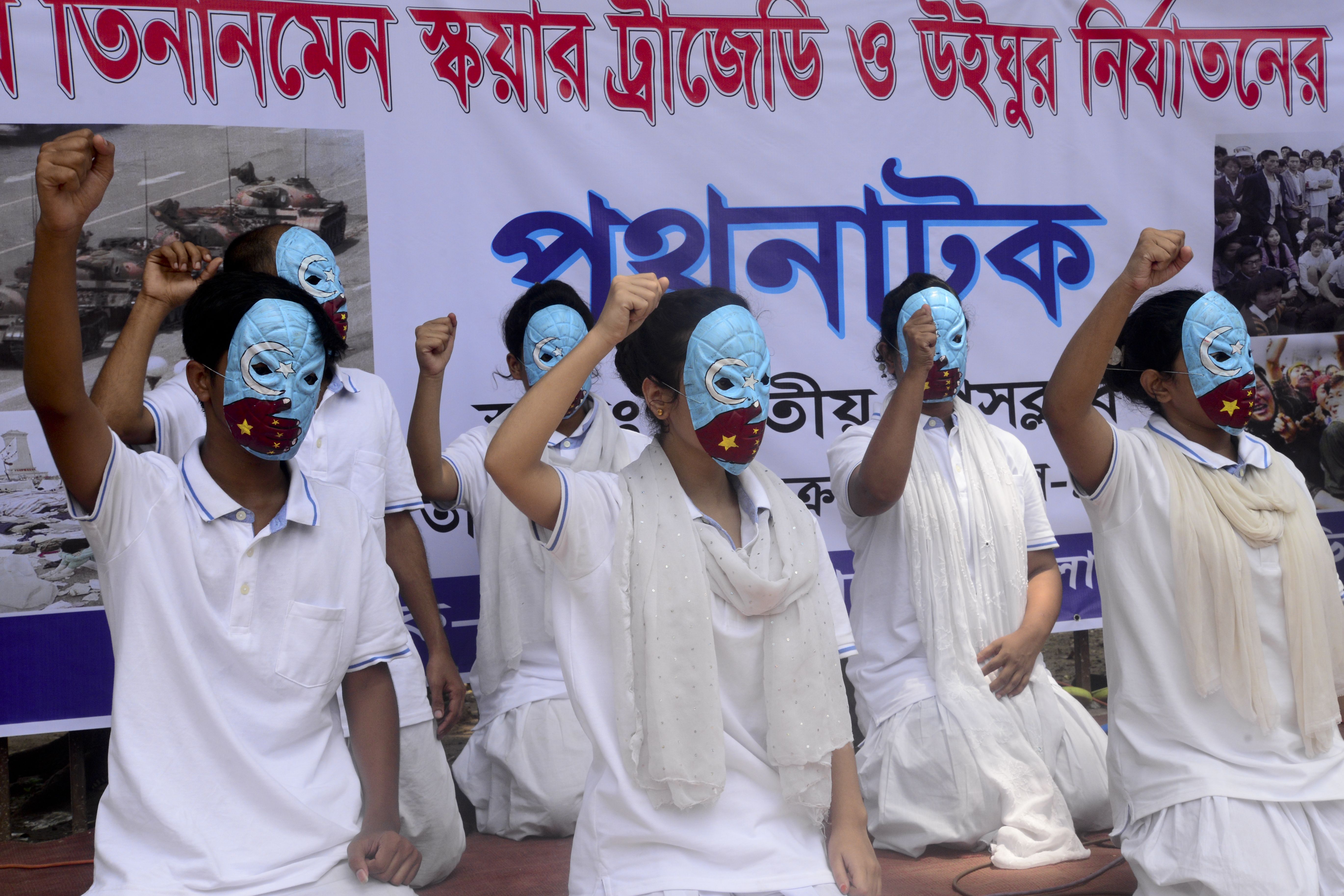 Photo of a group of social activists wearing blue masks and white clothing holding their fists up in protest against the Chinese government