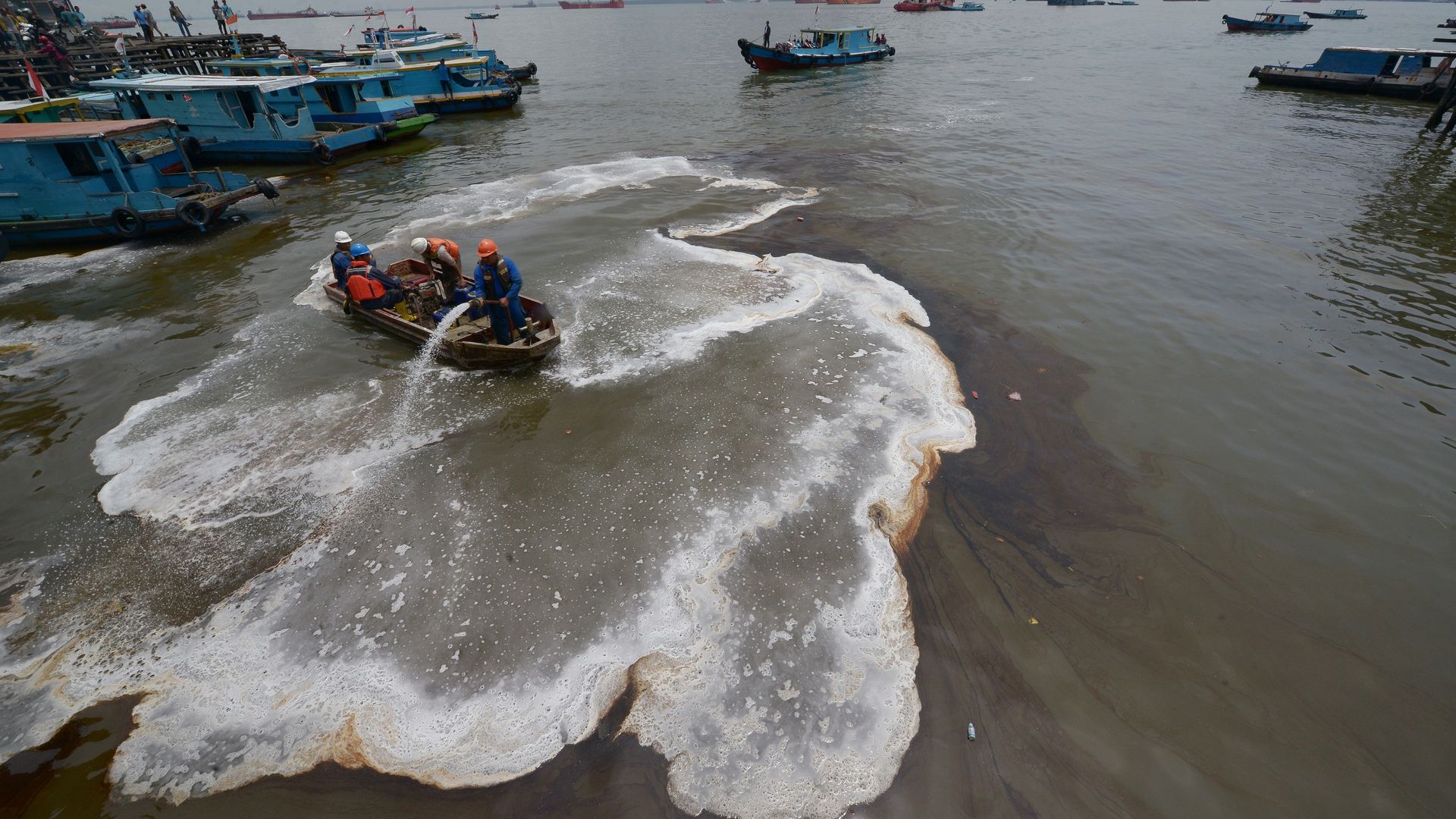 Indonesian workers trying to clean an oil spill from the sea in Balikpapan.