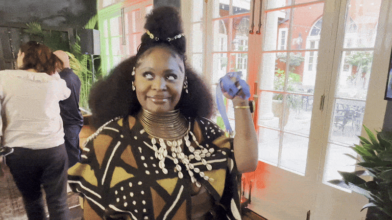 Image shows Tarriona Ball smiling and dancing with a bell.