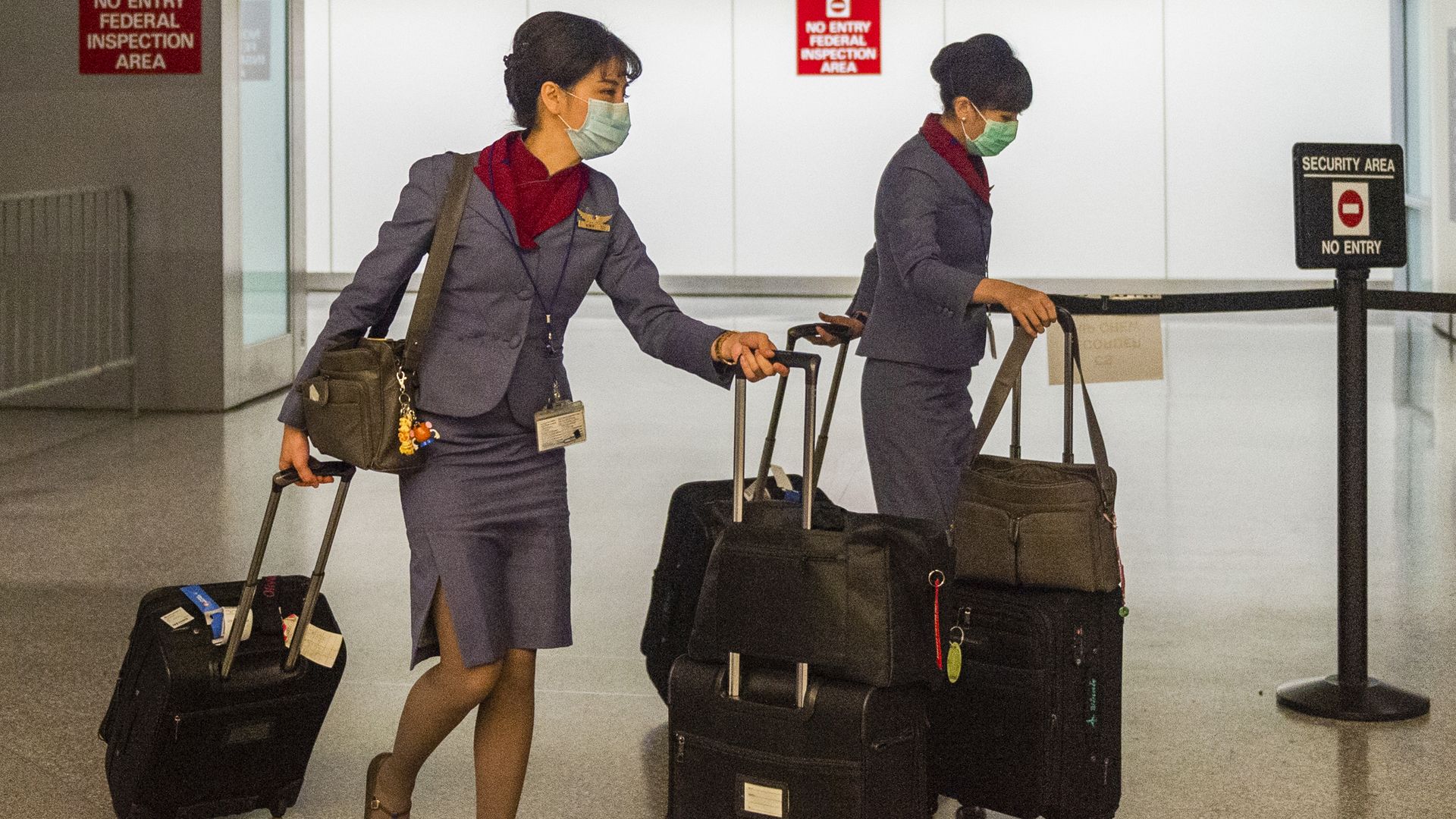 In this image, two flight attendants board a plane while wearing medical face masks.