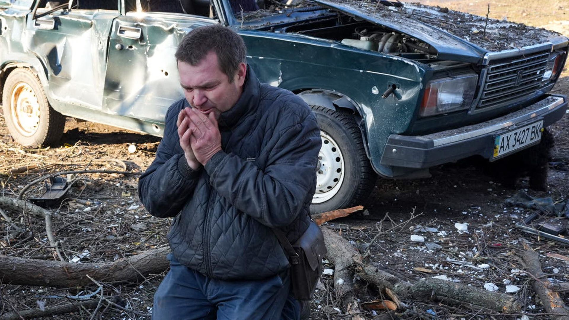 A man mourns near a body as airstrike damages an apartment complex outside of Kharkiv, Ukraine on February 24.