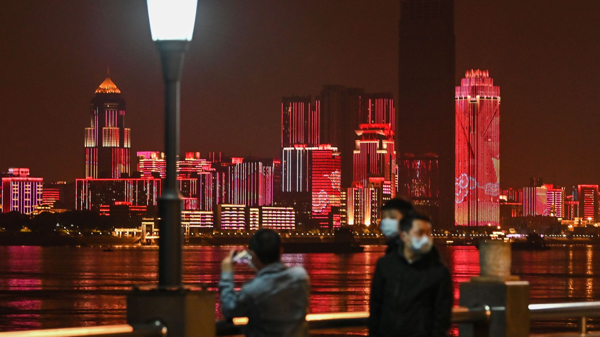 People wearing facemasks stand near Yangtze River in the city of Wuhan, in China's central Hubei province