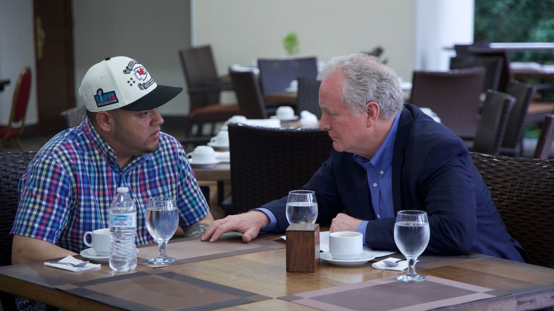 The detained Kilmar Armando Abrego Garcia and  Sen. Chris Van Hollen (D-Md.) at a table in a prison visiting room with glasses of water on it on Thursday.