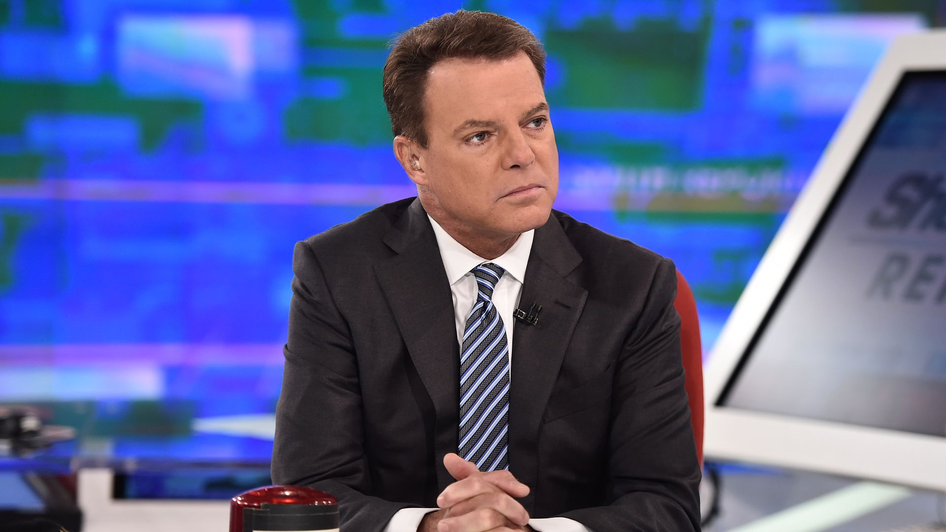 Shepard Smith sits in a suit and tie