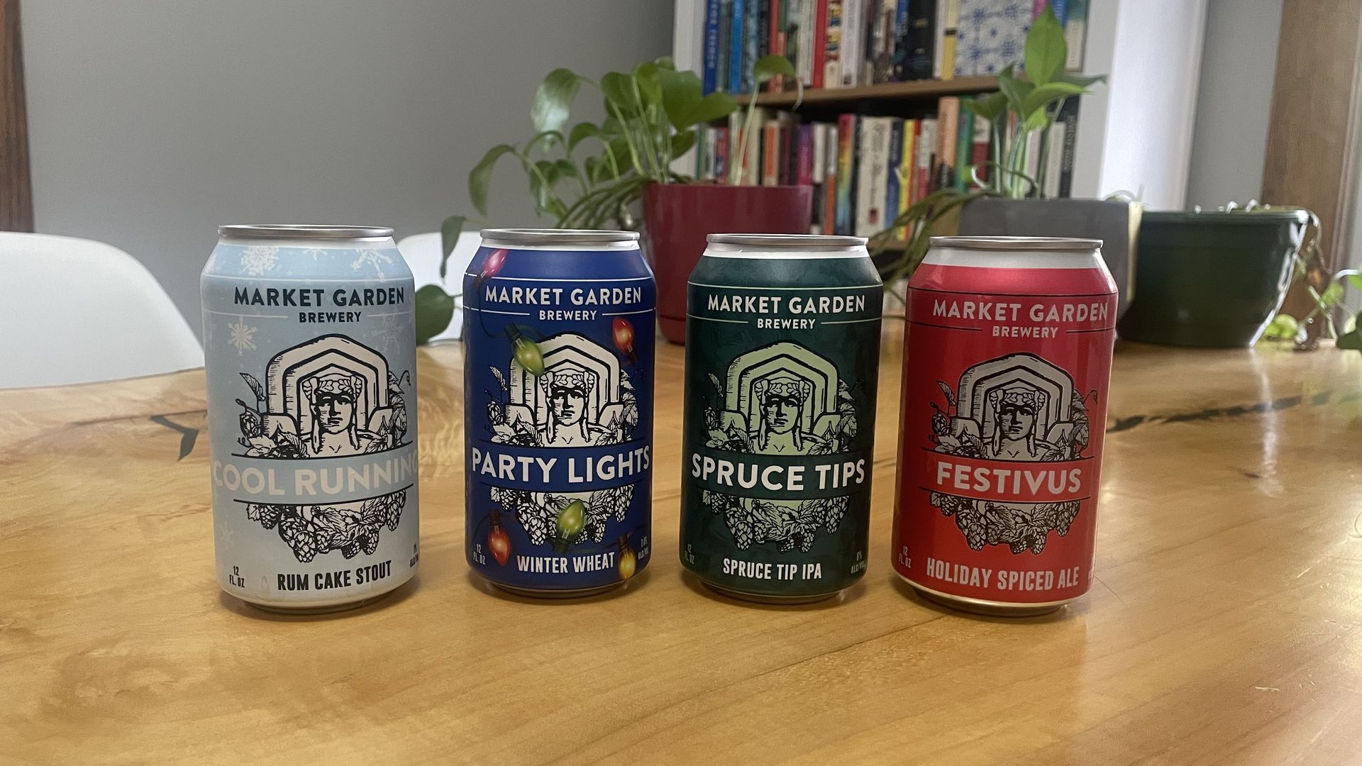Four holiday beers in a row in cans on a table