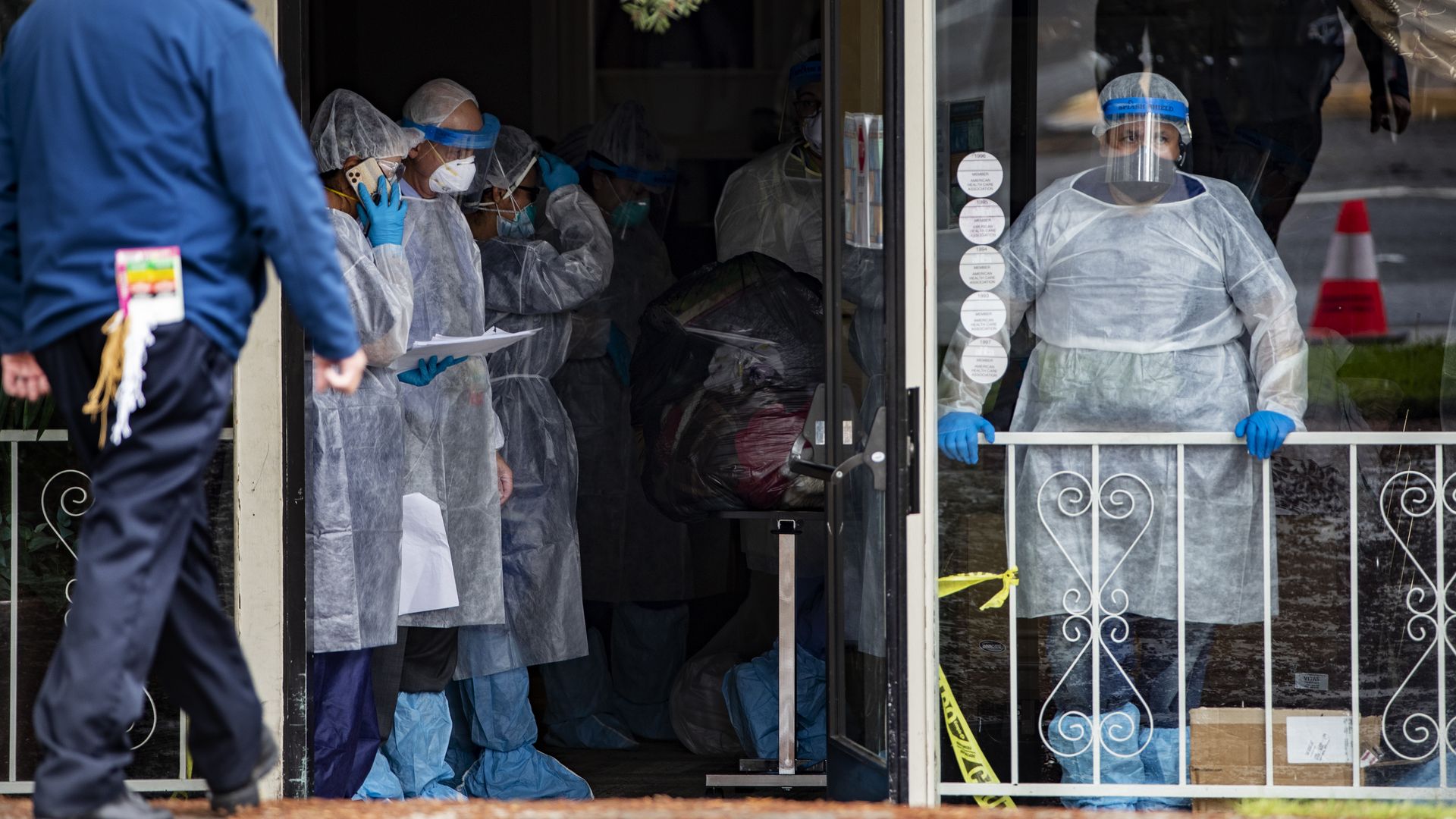 Medical staff in full personal protective gear line up to help remove patients from a nursing Center