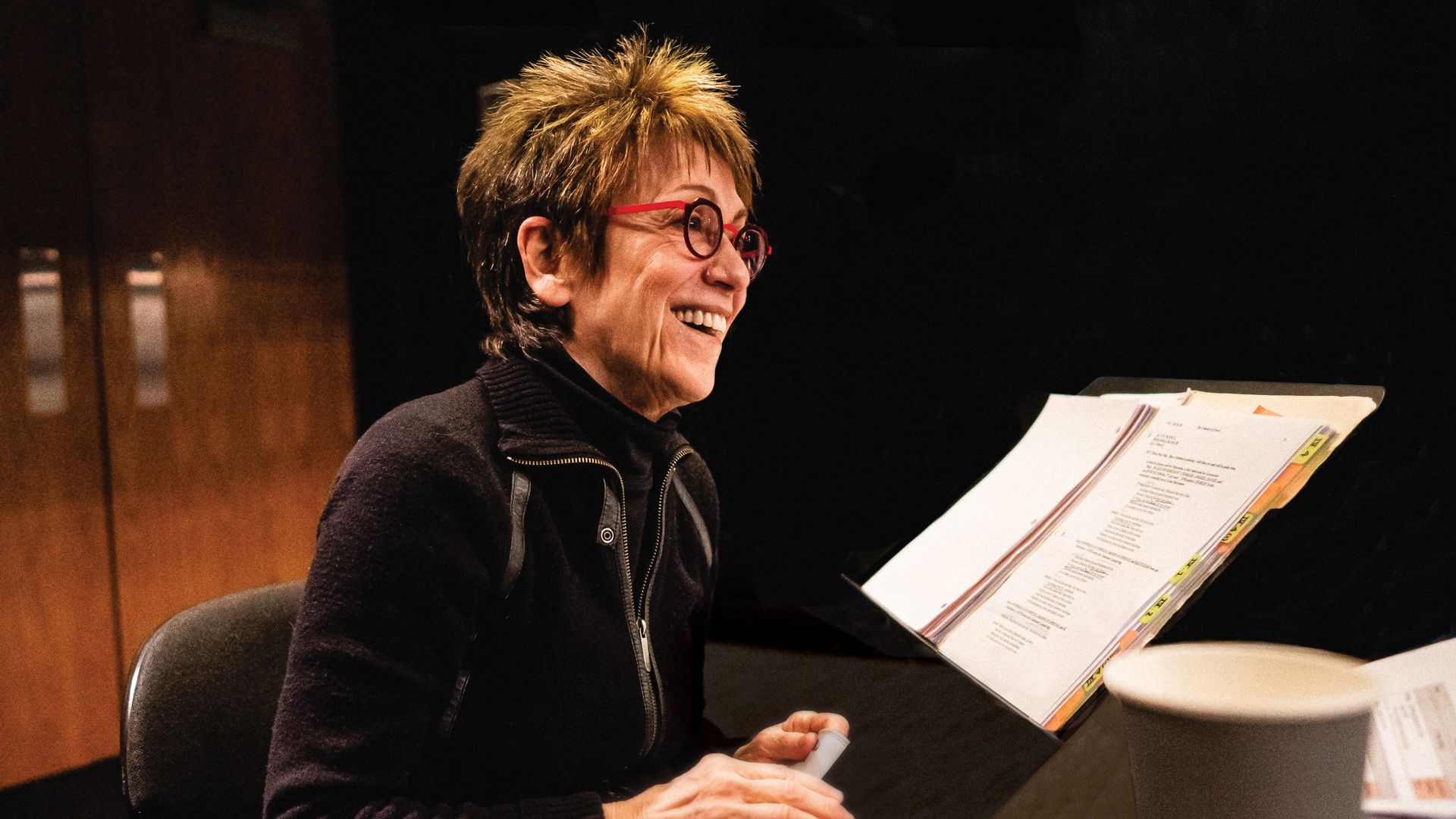 Photo of a woman reading a script at a table. 
