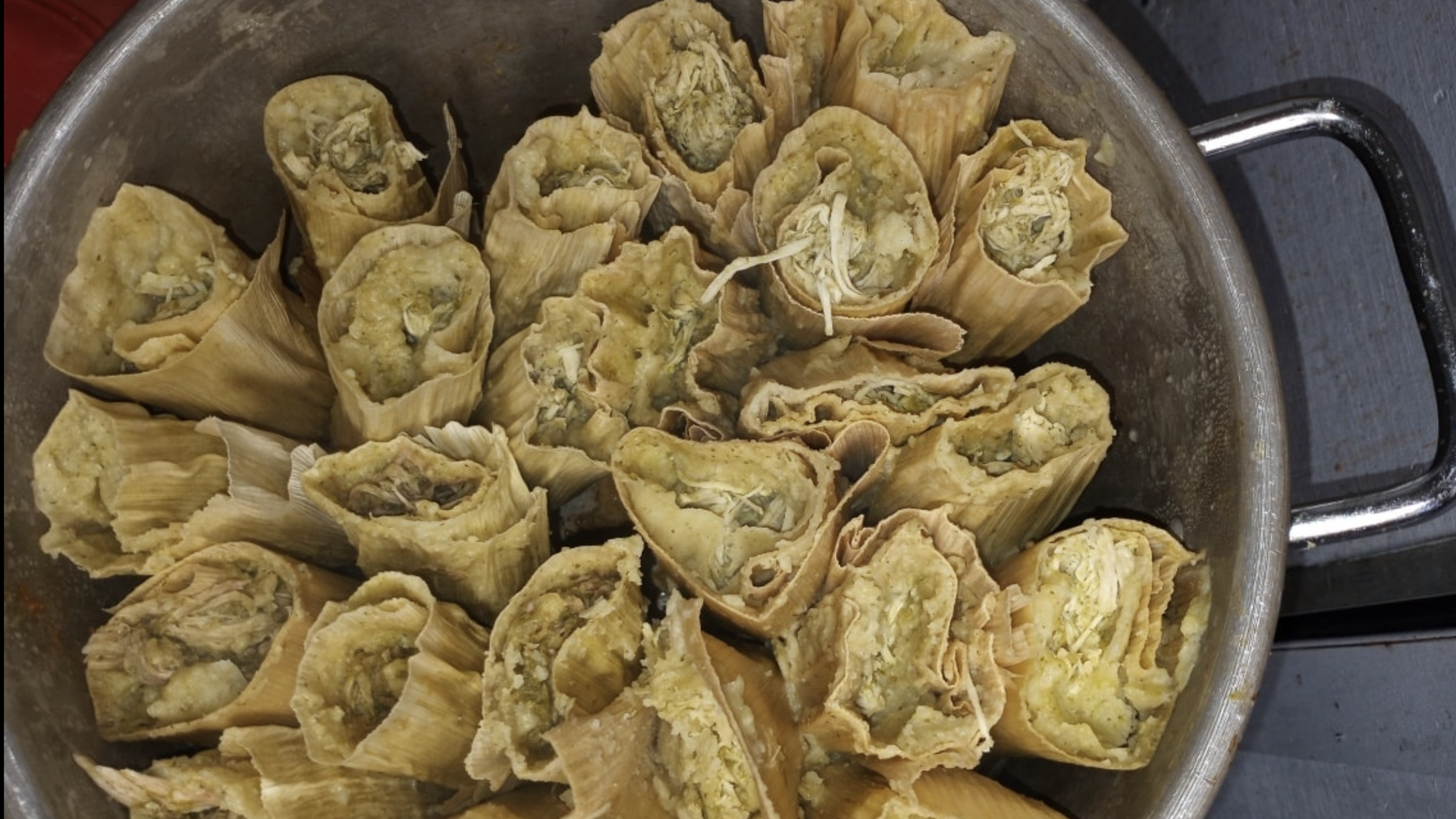 A pot filled with green tamales.