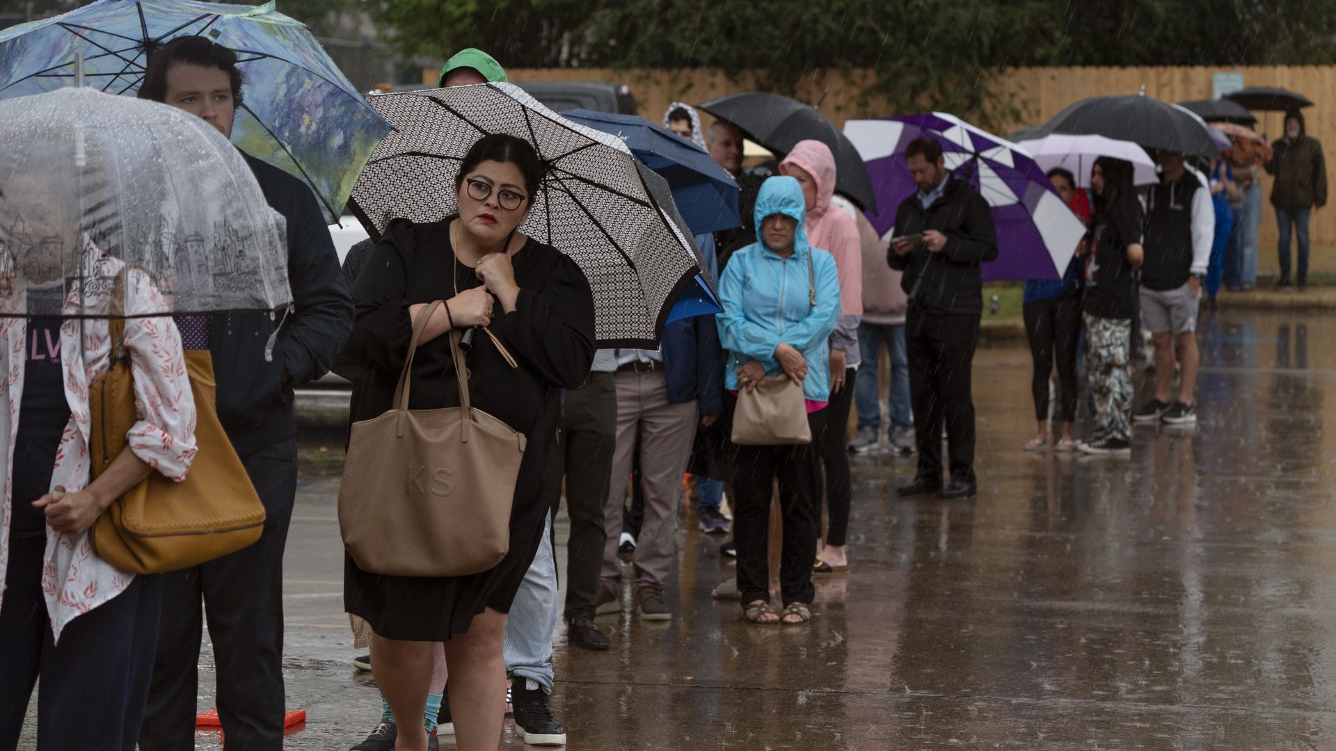 Photo of a crowd of people in line to vote with their umbrellas