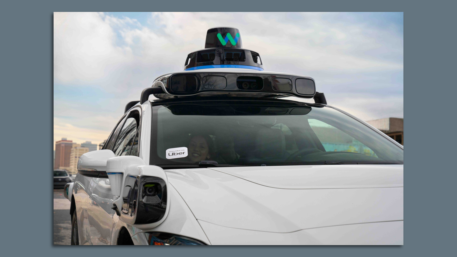 Close up of a Waymo robotaxi with an Uber sign in the windshield. 