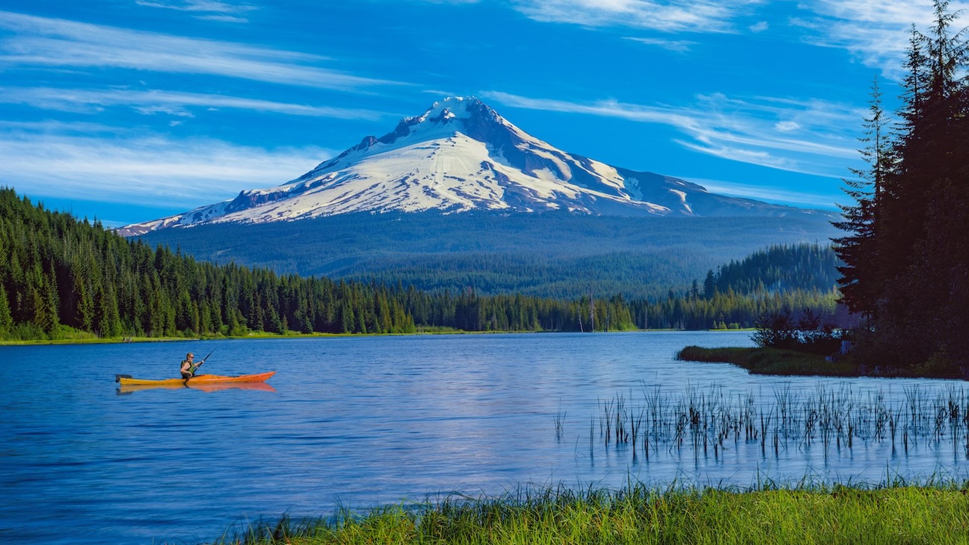 A photo of a snow-capped mountain with a lake and a kayaker on it.