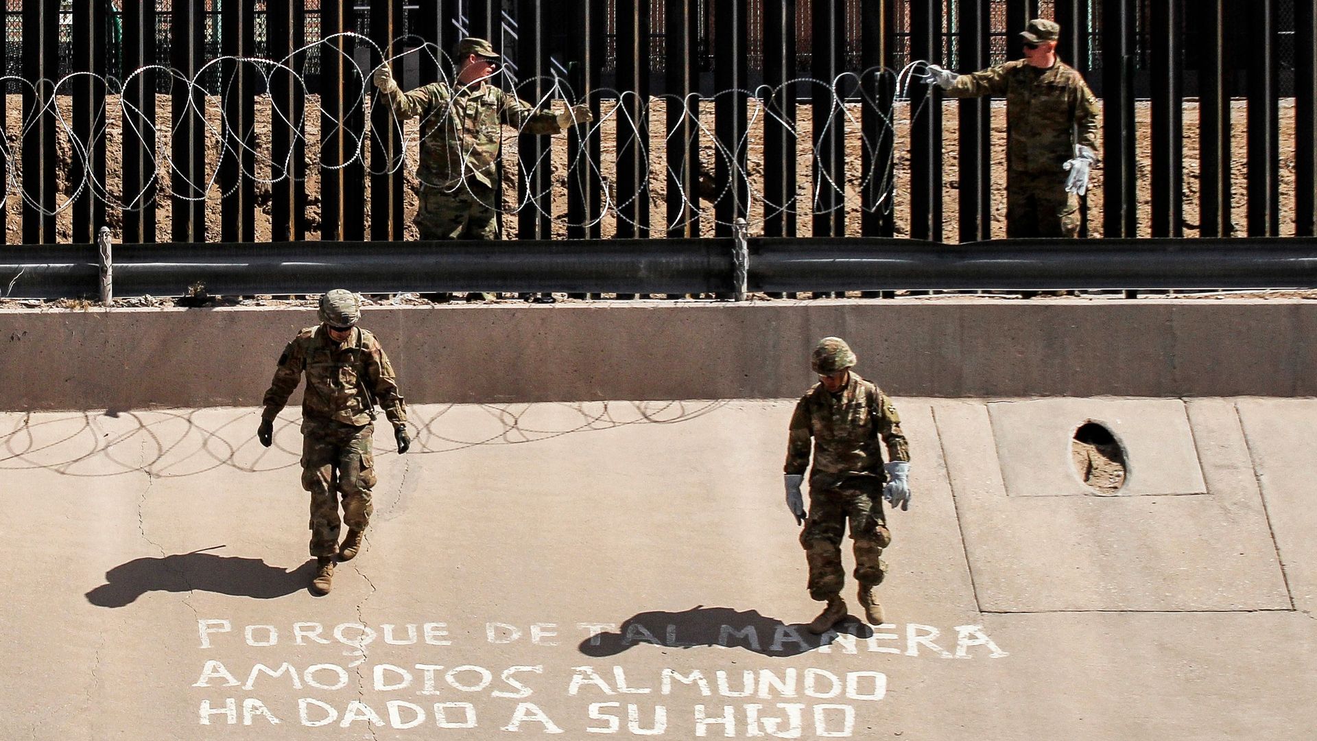 U.S. soldiers install barb wire by the US-Mexico border fence.