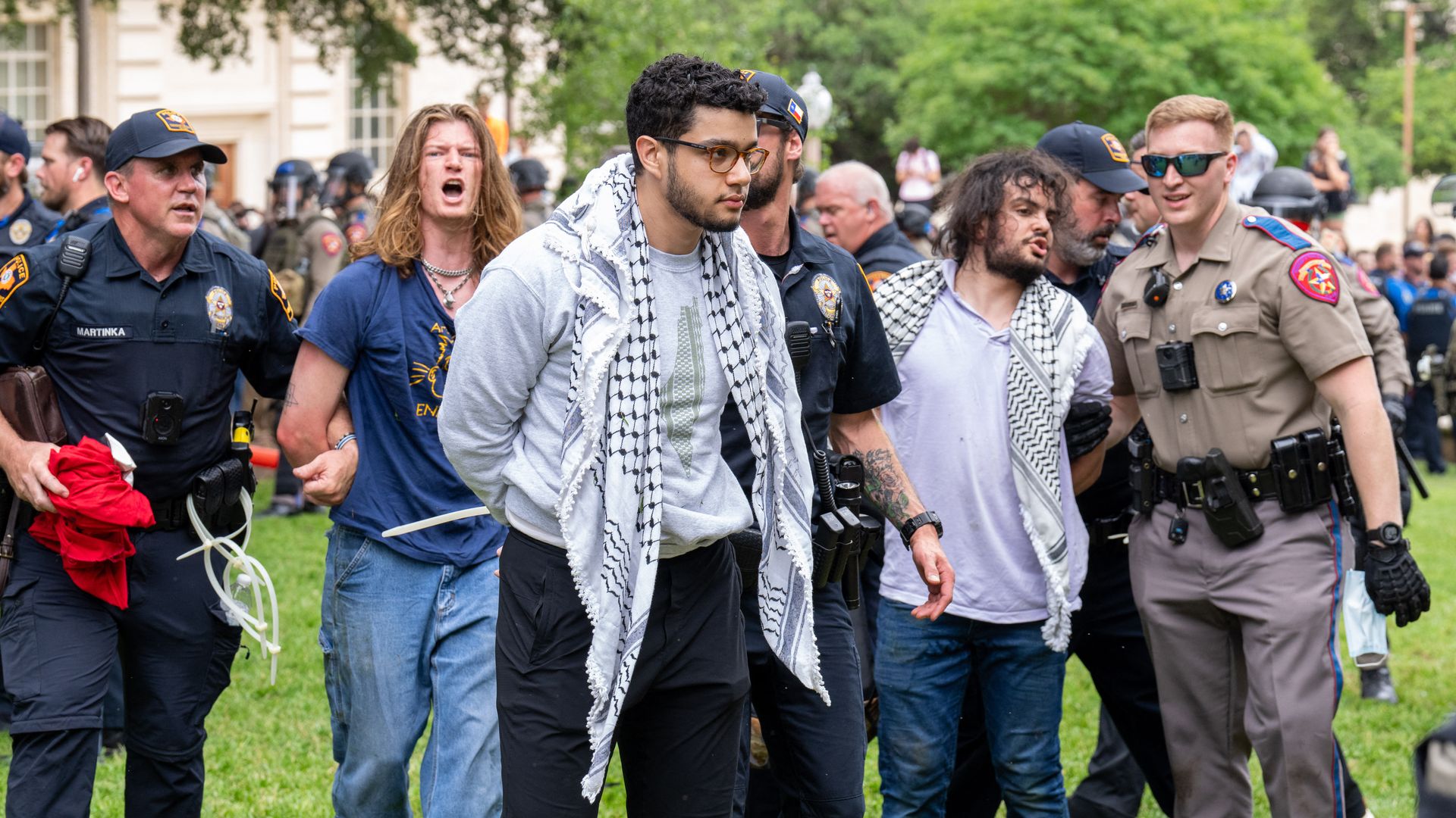 Protesters are arrested by police on a university lawn.