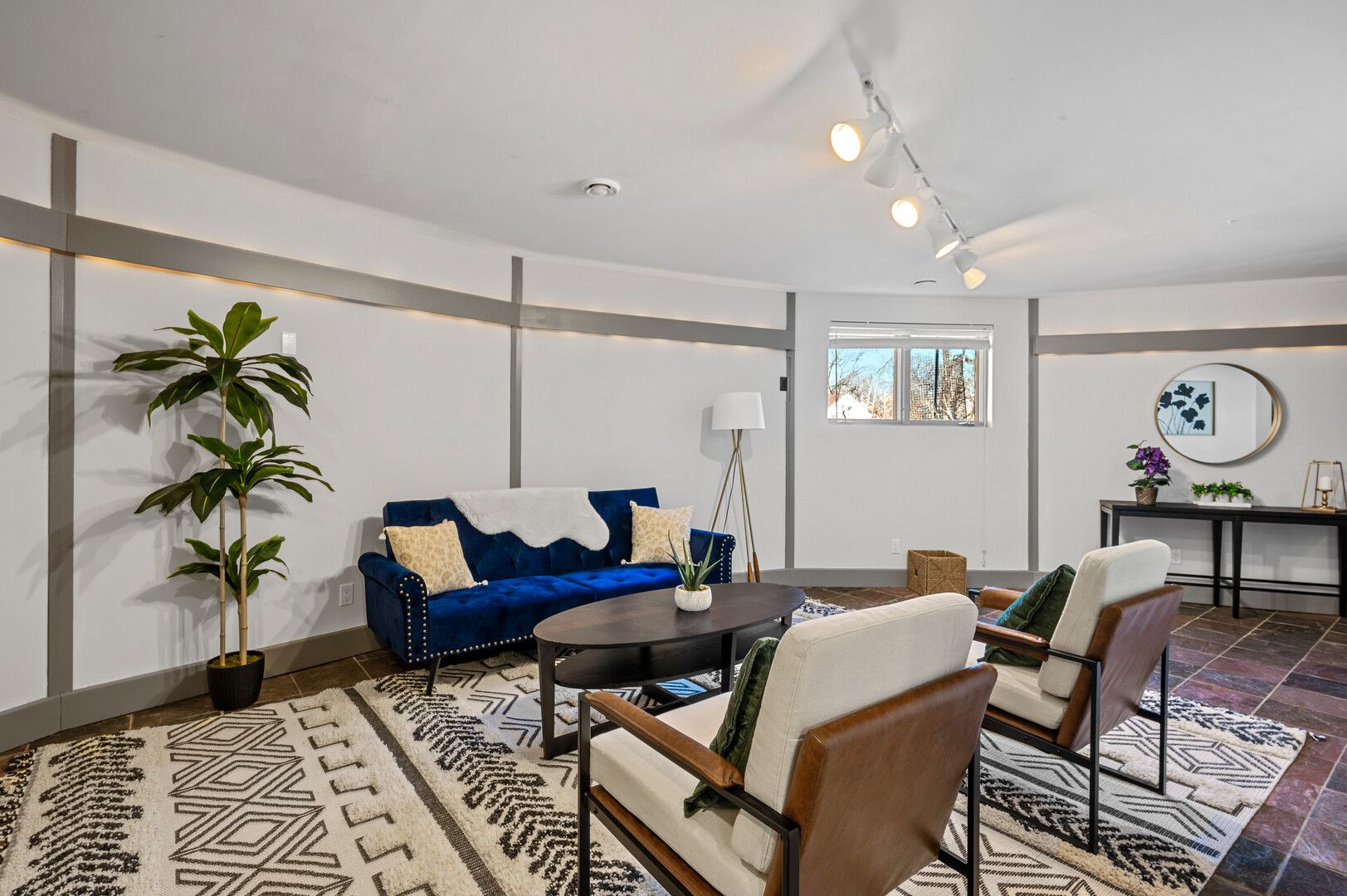 A basement with white walls, blue and white furniture and a small window.